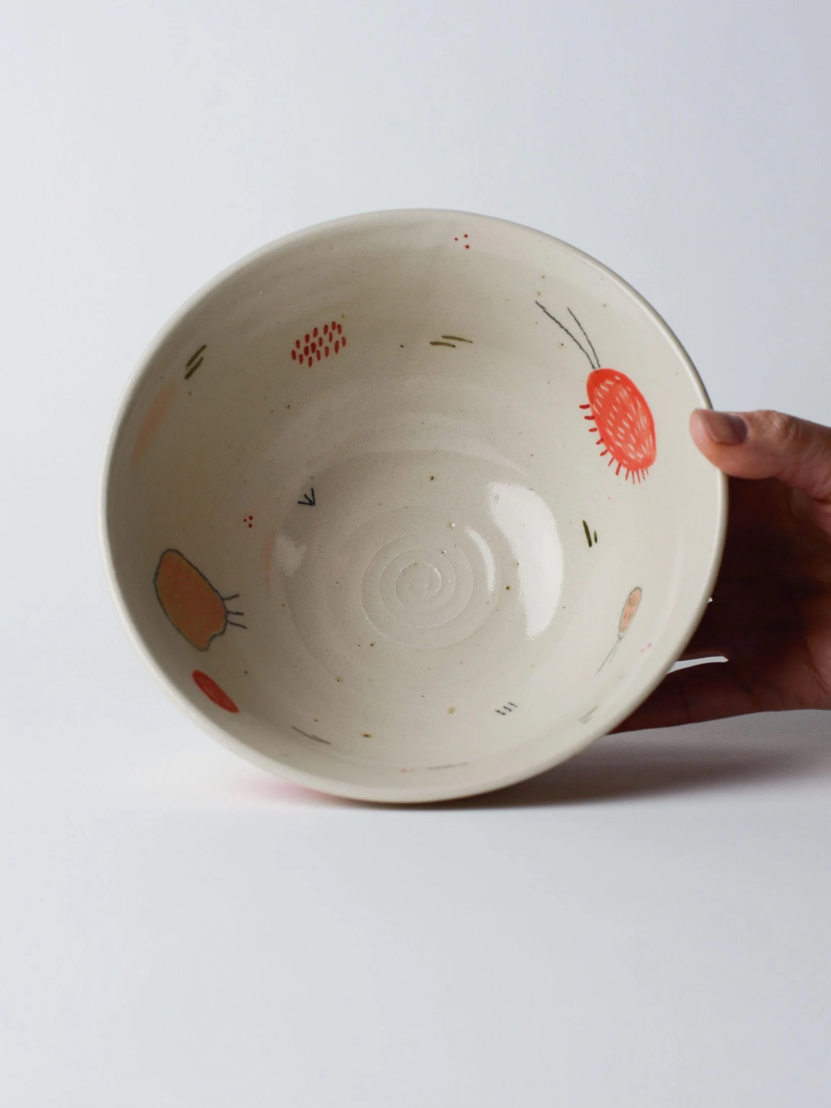 Udon-Schale mit kleinen gezeichneten Wesen – in der Hand gekippt, zeigt die innen glasierten Flächen.