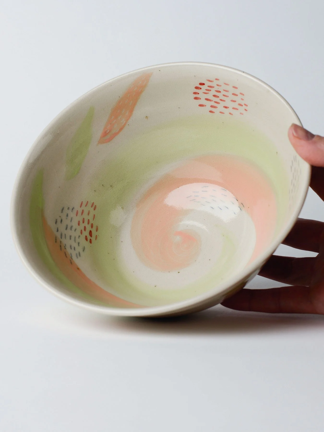 Udon-Schale mit zartgrünem Pinselstrich – gekippte Schale in der Hand, Innenglasur sichtbar.