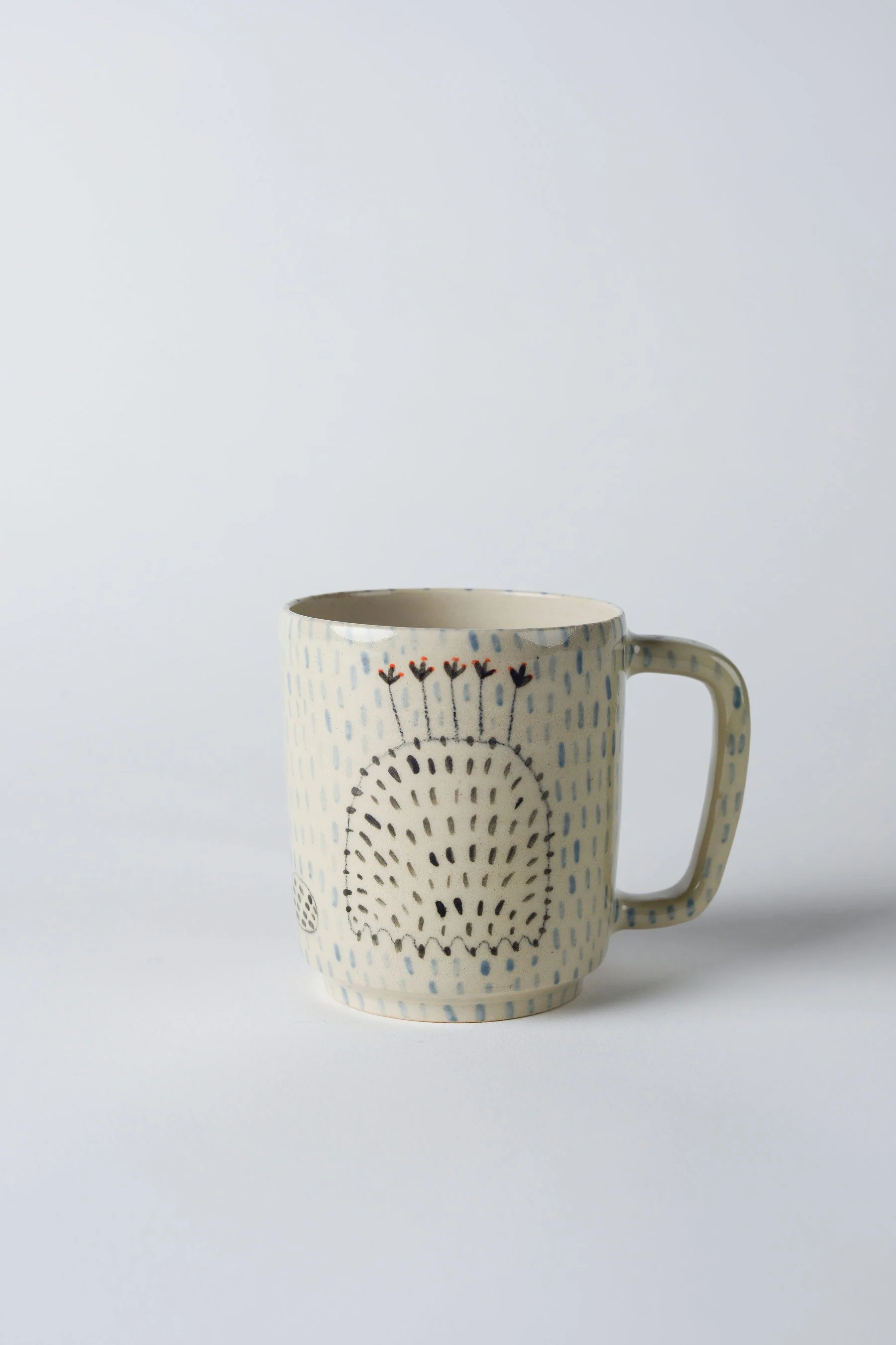 Ko-hi-Tasse aus Keramik mit dem gezeichneten schwarzen Wesen – weitere Drehansicht, um das umlaufende Motiv sichtbar zu machen.