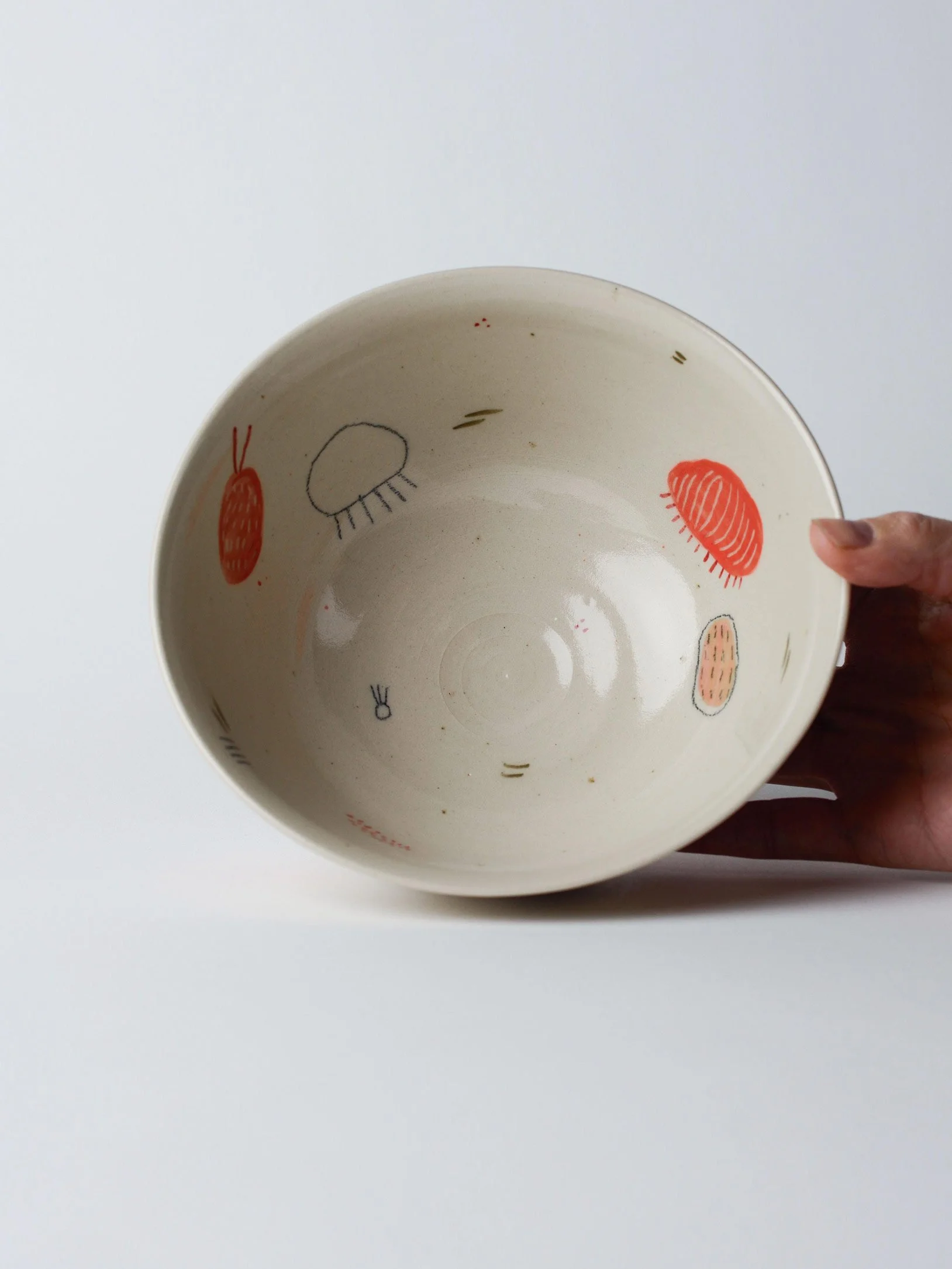 Udon-Schale mit kleinen gezeichneten Wesen – in der Hand gekippt, zeigt die innen glasierten Flächen.