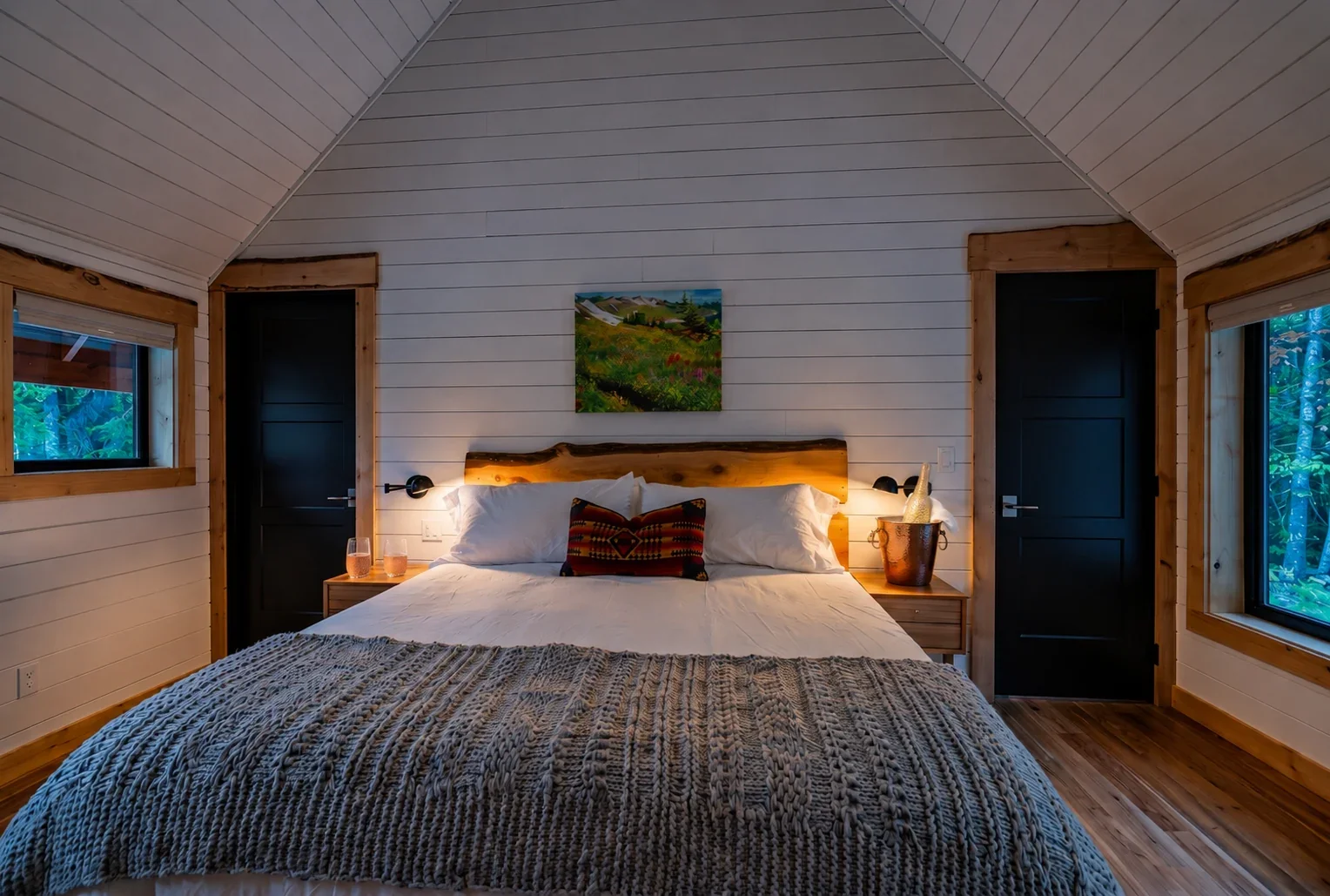 Fjellsangin honeymoon king bedroom — cedar headboard, champagne on ice, sconce glow, forest view at dusk, Ashford WA