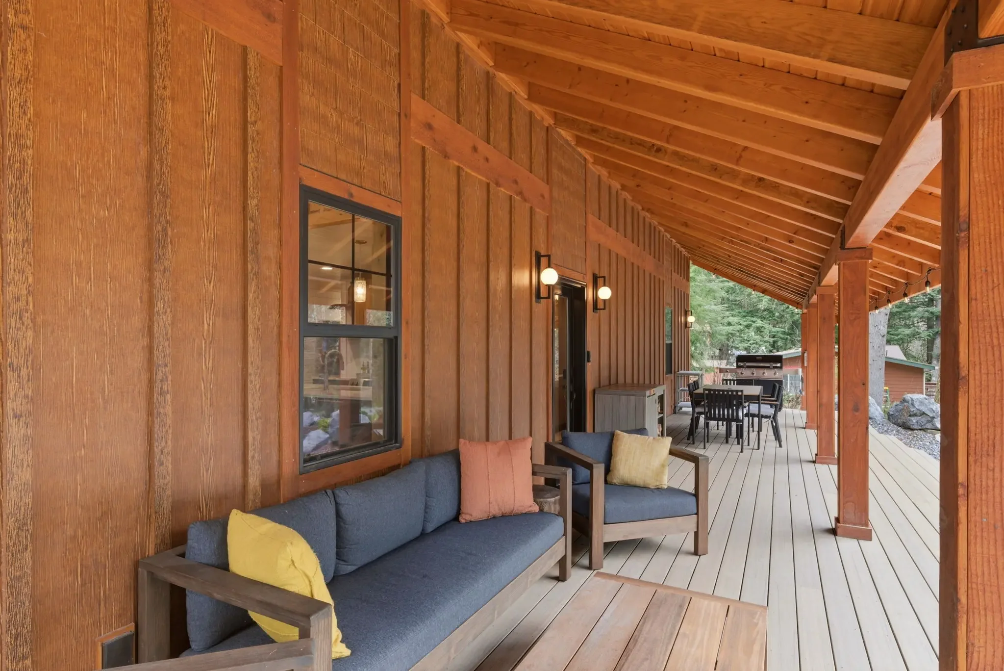 Covered porch with outdoor sofa and colorful pillows at Fjellsangin cabin