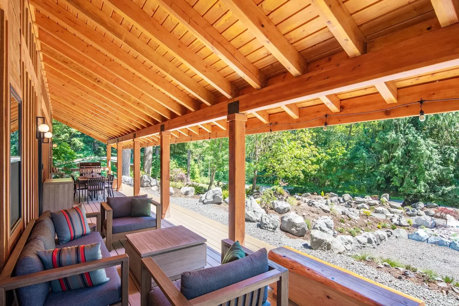Covered deck lounge with striped bolster cushions and garden view at Fjellsangin near Mount Rainier
