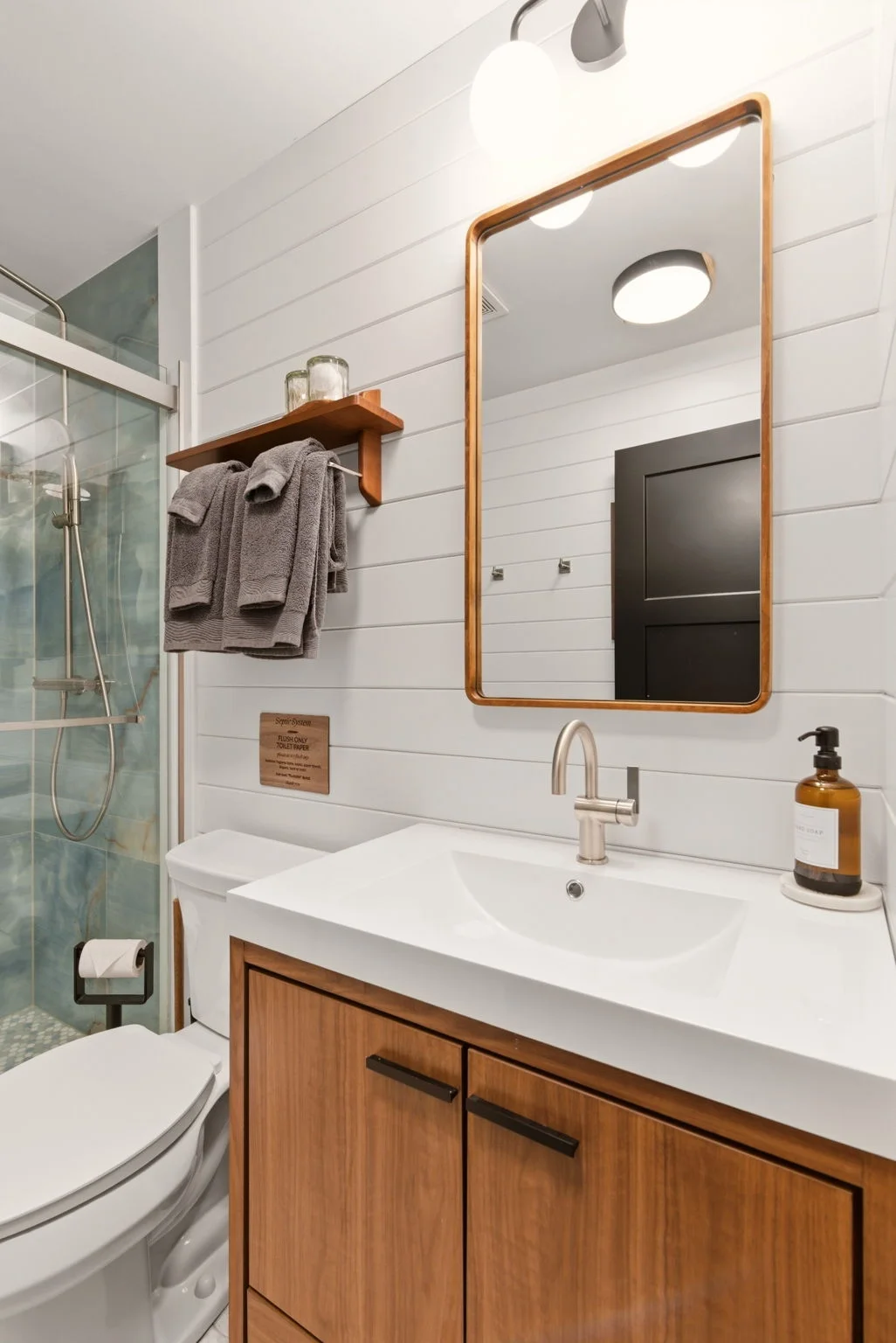 Main bathroom vanity with walnut cabinetry and v-groove walls at Fjellsangin cabin