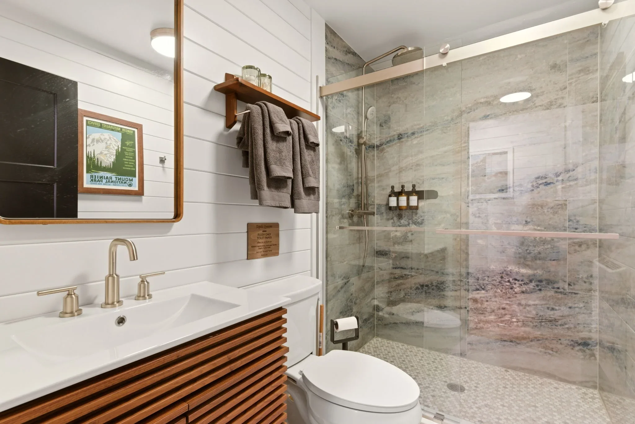Walk-in shower with grey marble-look tile and walnut vanity at Fjellsangin cabin near Mt. Rainier