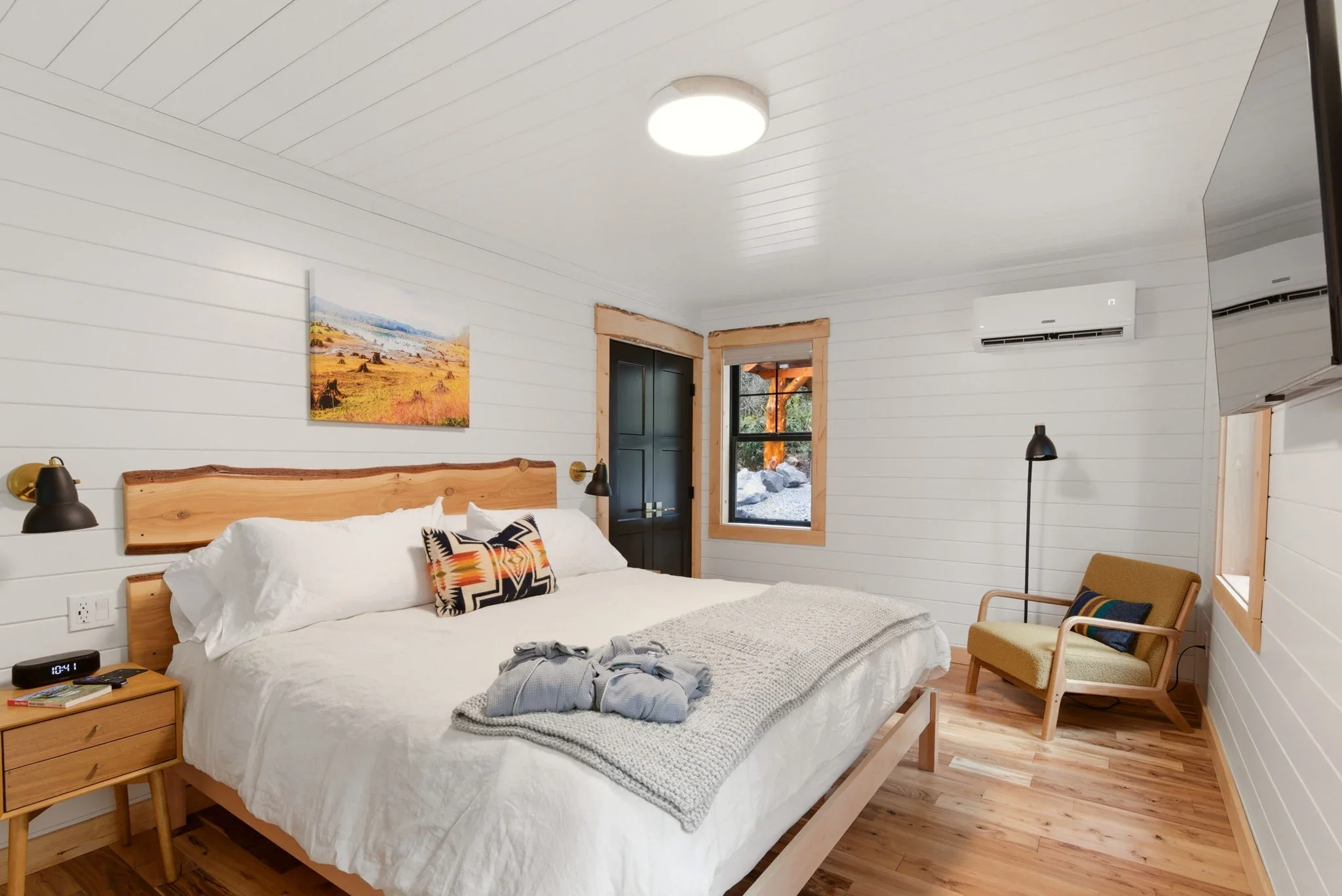 Main level king bedroom at Fjellsangin with live-edge cedar headboard and white v-groove walls
