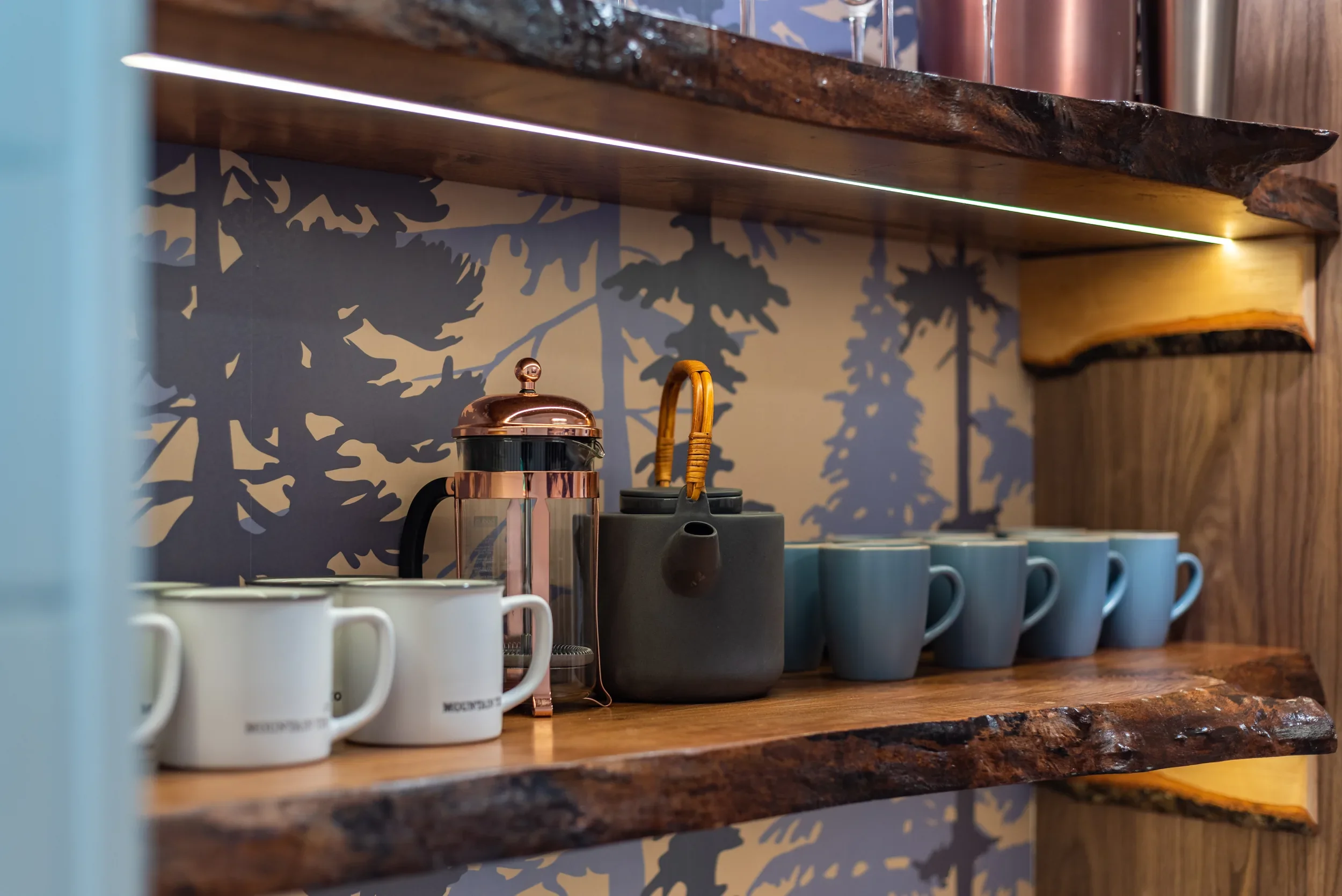 Teal mugs on the live-edge maple shelf at the Fjellsangin coffee bar with custom tree wallpaper