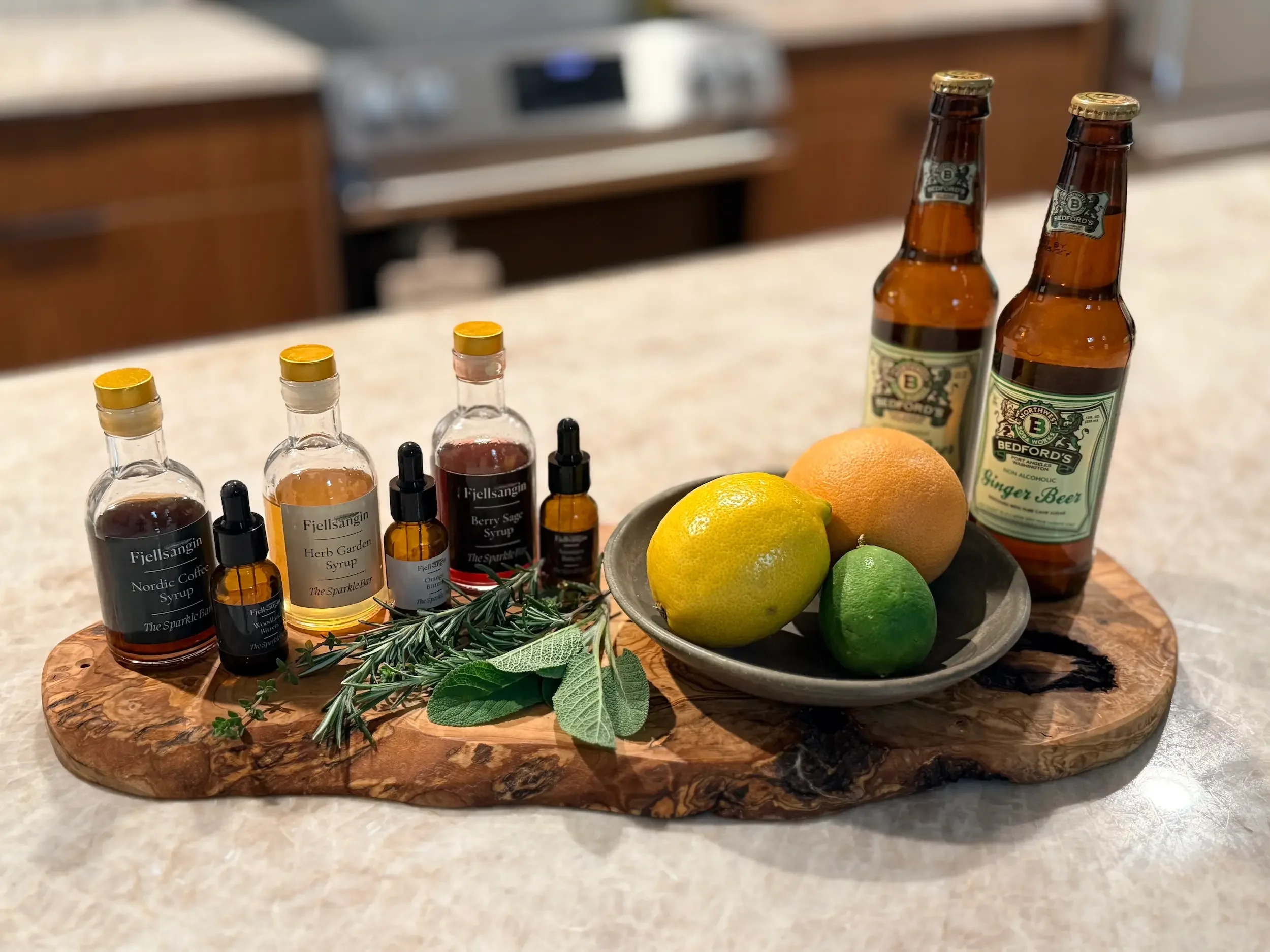 Fjellsangin Sparkle Bar Kit with Nordic Coffee, Herb Garden, and Berry Sage syrups, bitters, fresh herbs, citrus, and Bedford's ginger beer on the Taj Mahal quartzite kitchen counter
