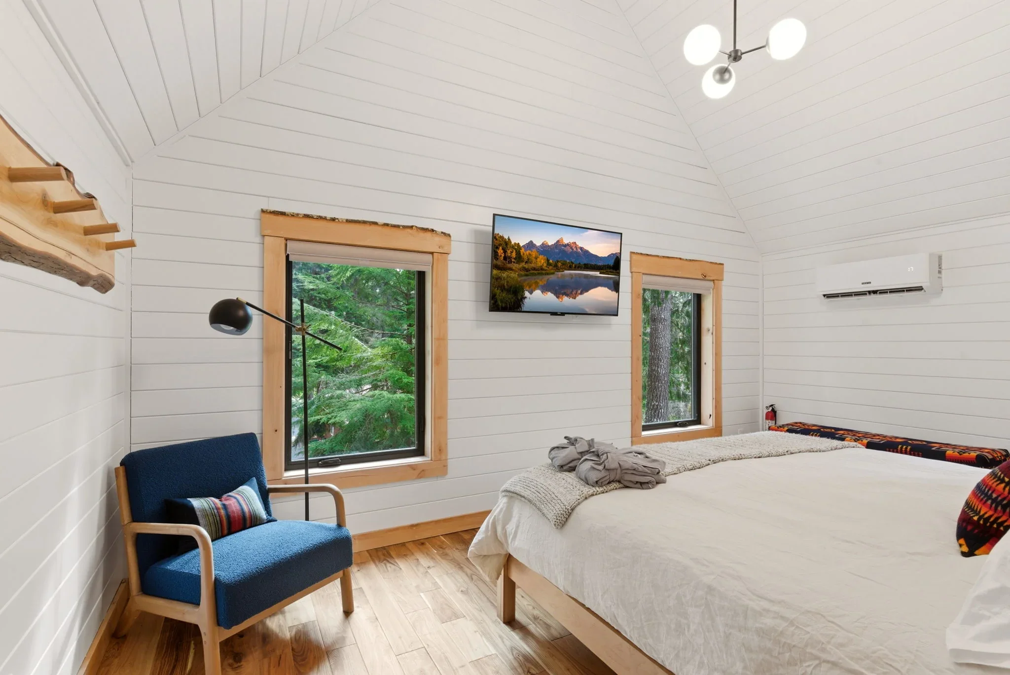 Upper king bedroom wide view with cedar headboard and forest windows at Fjellsangin