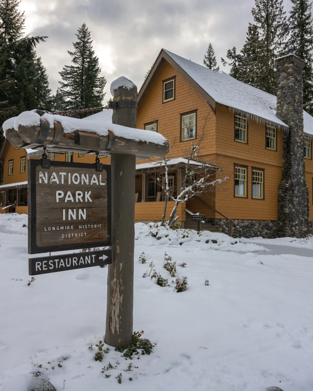 Snow-covered National Park Inn sign and the inn at Longmire in Mount Rainier National Park in winter