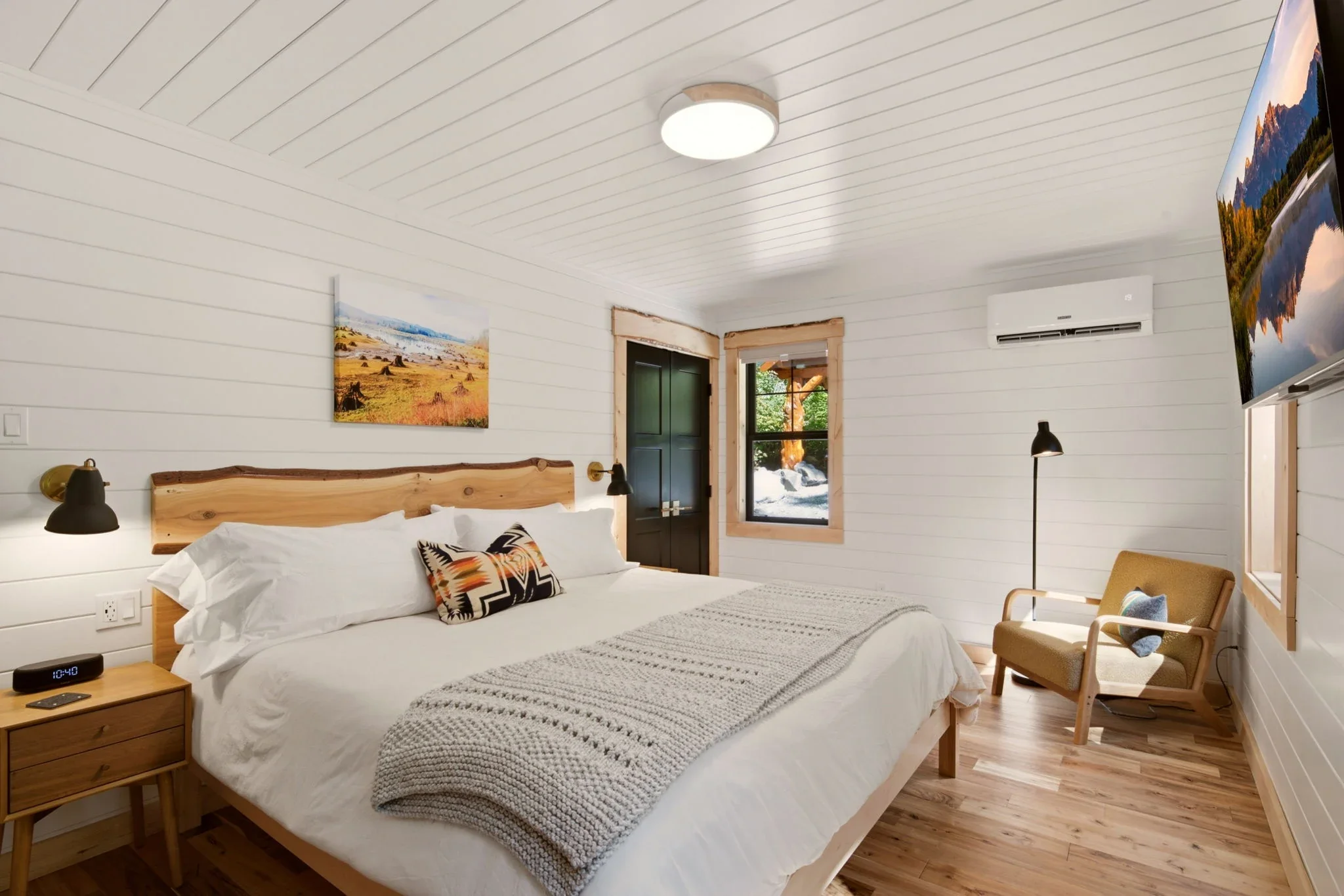 Main-floor bedroom with cedar headboard, black sconces, and armchair at Fjellsangin cabin near Mount Rainier