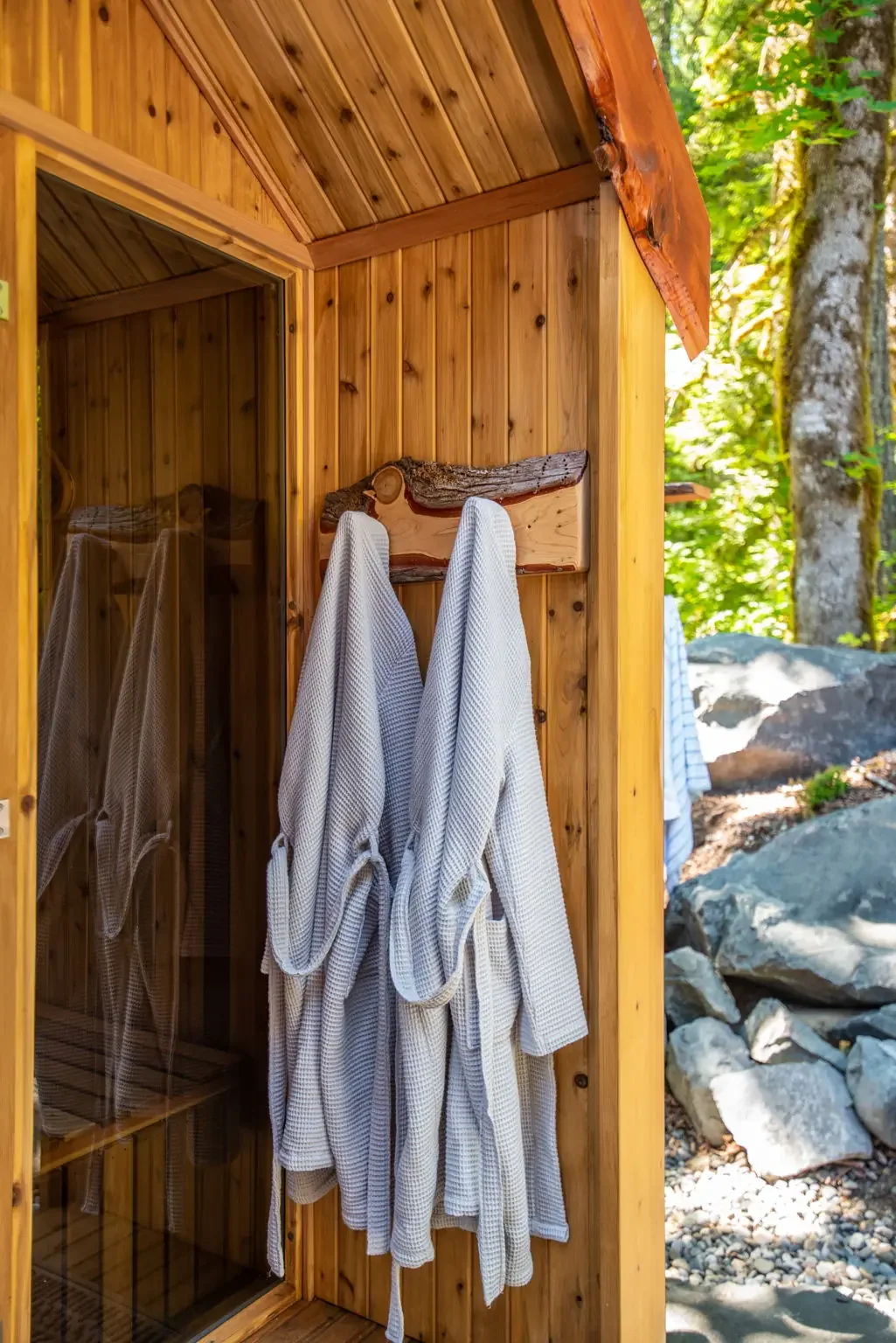 Cedar-lined sauna exterior with robes hanging on live-edge cedar hooks at Fjellsangin cabin near Mount Rainier