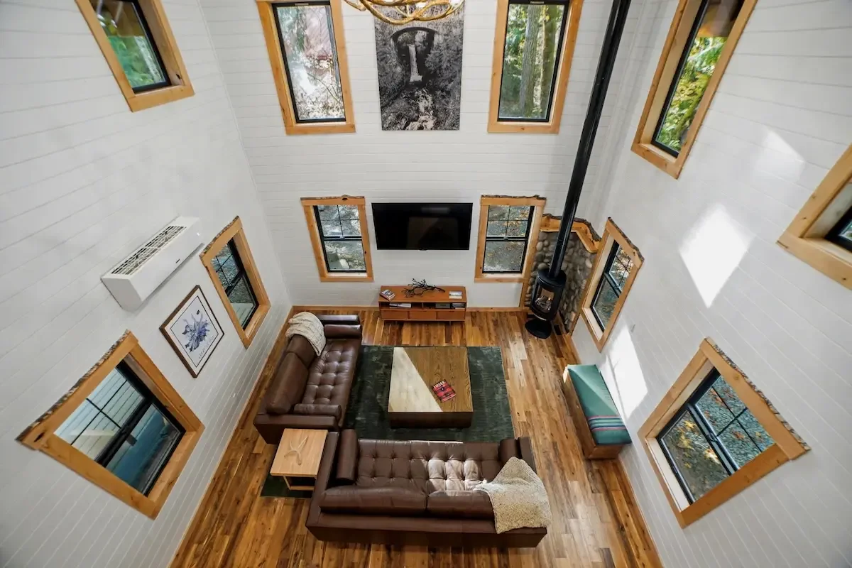 View from the loft into Fjellsangin's great room with old-growth forest visible through the windows