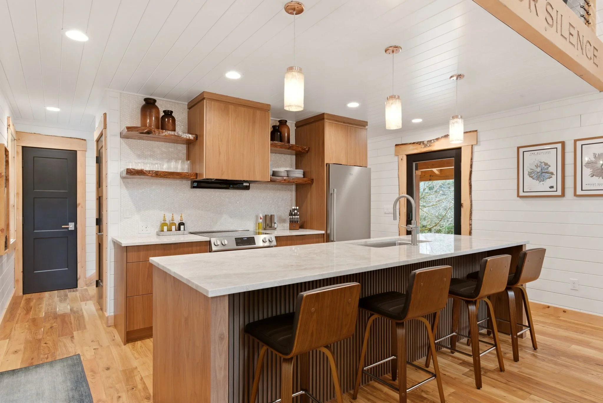 Full kitchen at Fjellsangin with walnut cabinetry, mother-of-pearl backsplash, and live-edge shelving