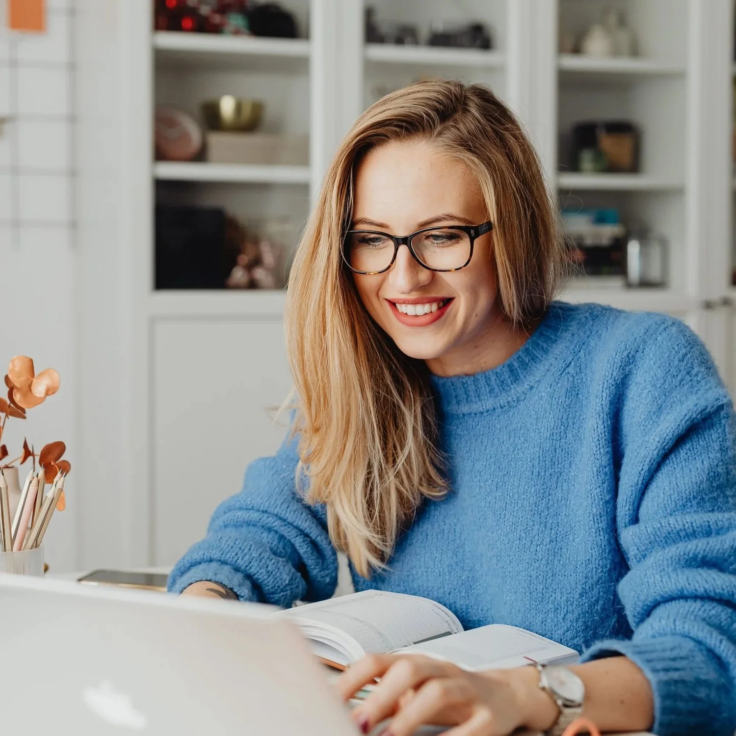 A woman at a table at home during an online therapy session on her laptop