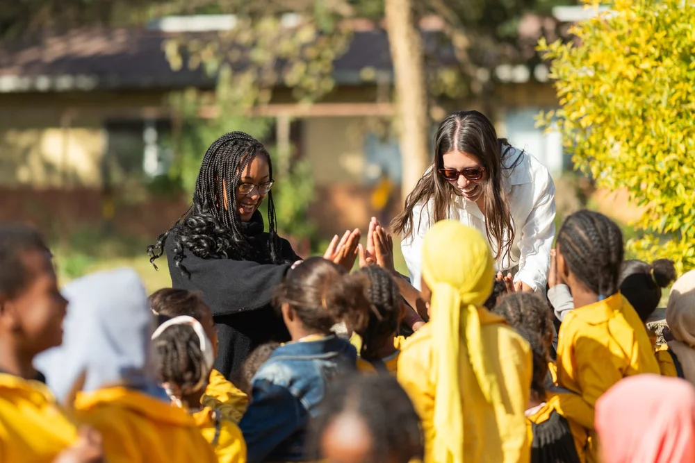 Jordan Wright sharing a high-five with a group of children outdoors during community program work