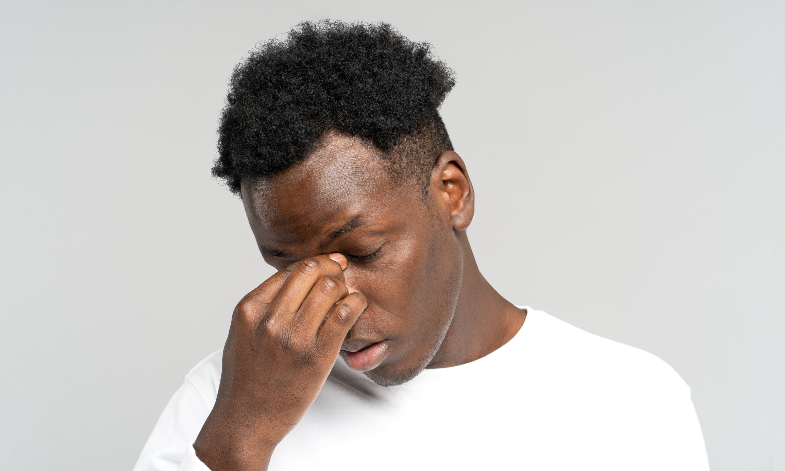 Black man in business attire looking out a window, symbolizing quiet burnout behind professional success.