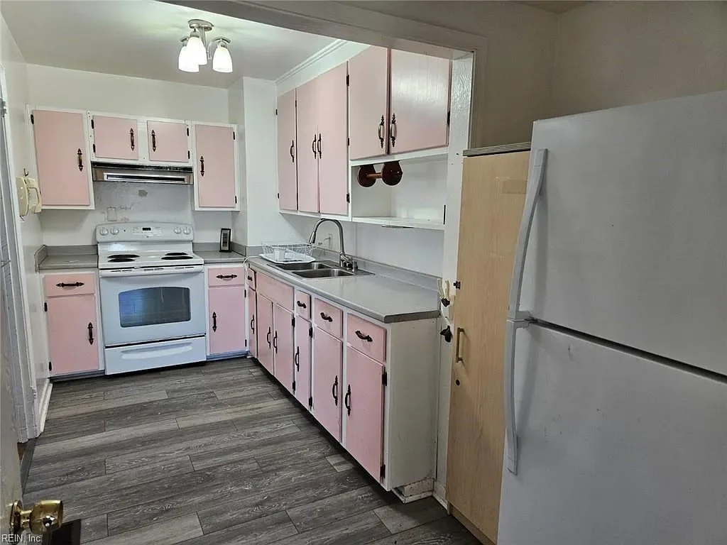 Before-renovation view of a dated kitchen with pink cabinets, purchased by JDK Strategic Solutions to provide a fast closing for the homeowner.