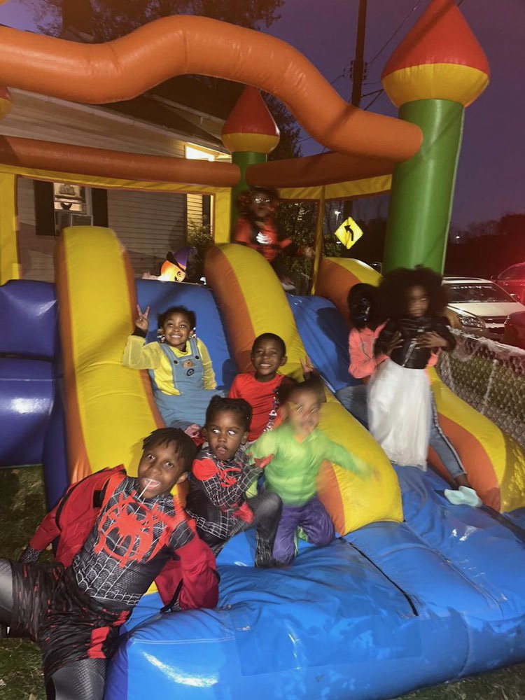 Children playing on a colorful inflatable slide at night, smiling and making peace signs.