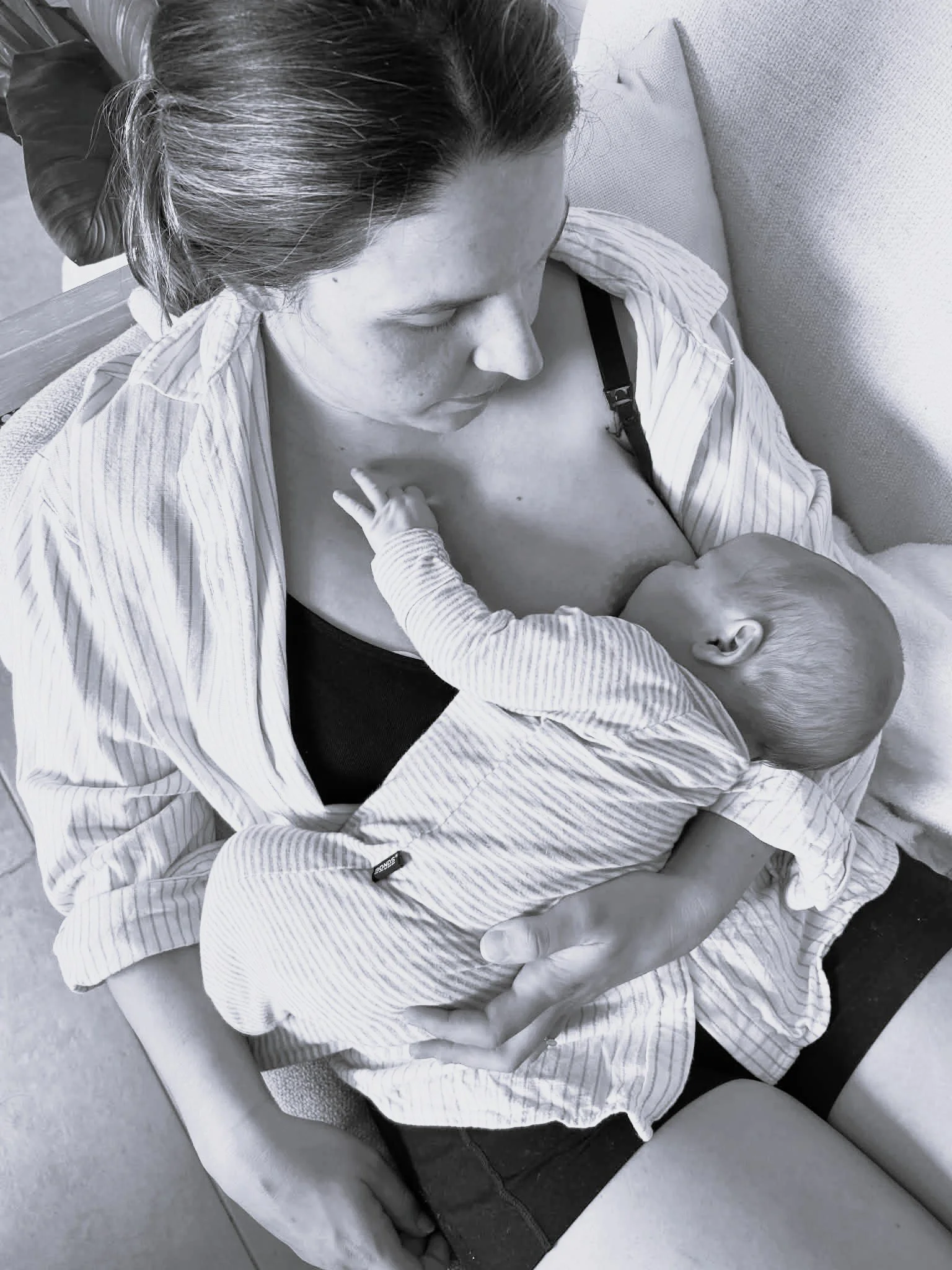 Mother breastfeeding her newborn during an in-home lactation consultation with a PostPartum midwife.