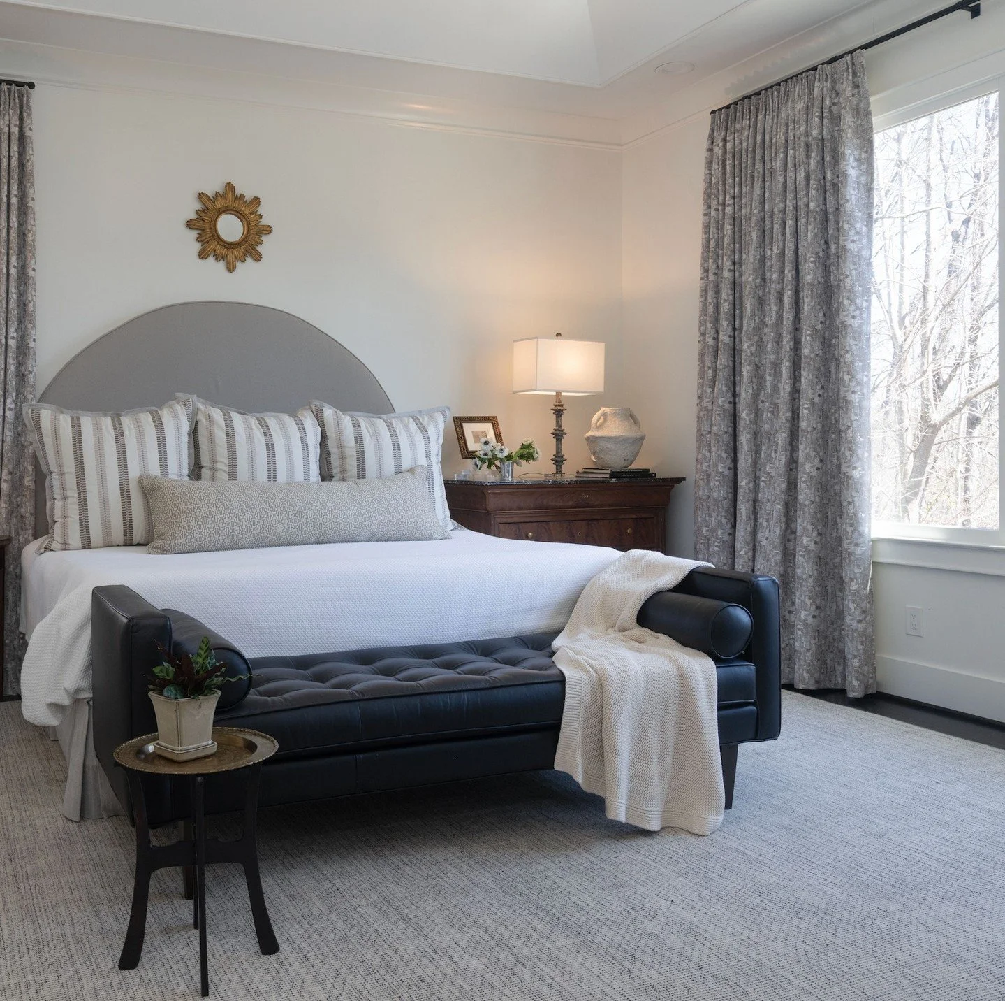 This primary suite started as a blank slate with basic pocket rod curtains &mdash; and what a difference a year makes. Custom drapes now dress every window, adding the kind of weight and warmth you simply can't get off the rack. A custom-cut rug with