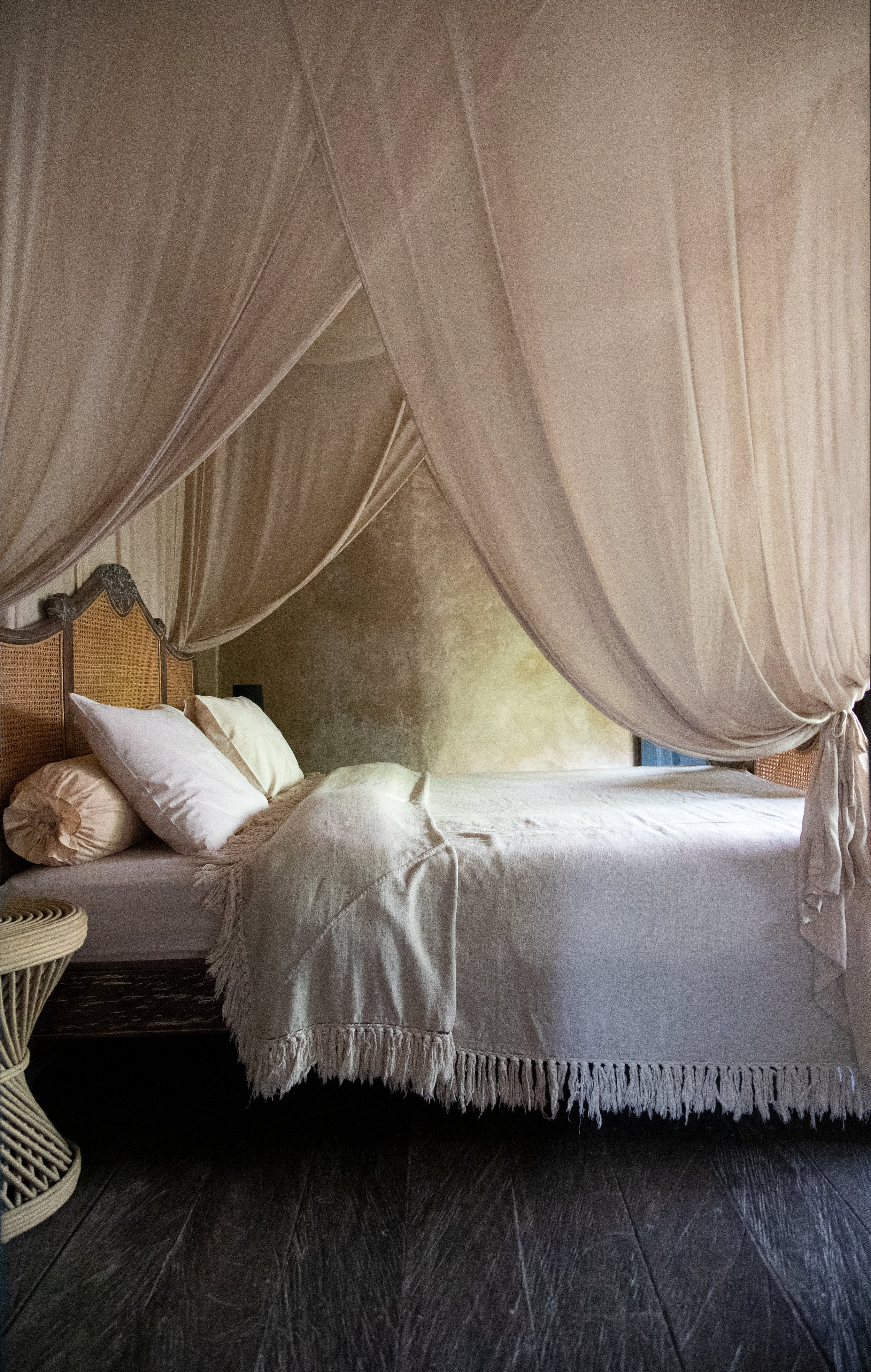 Cozy bedroom with canopy bed, sheer drapes, and neutral bedding.