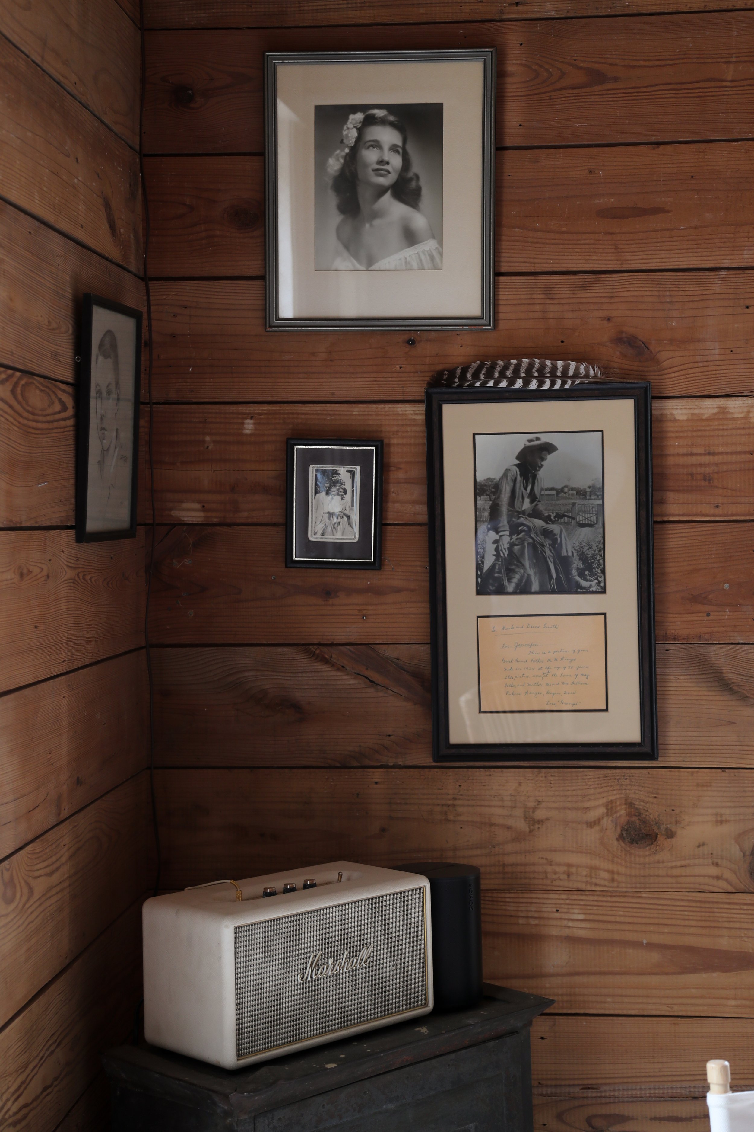 Wooden wall with framed vintage photographs and a Marshall speaker on a table.