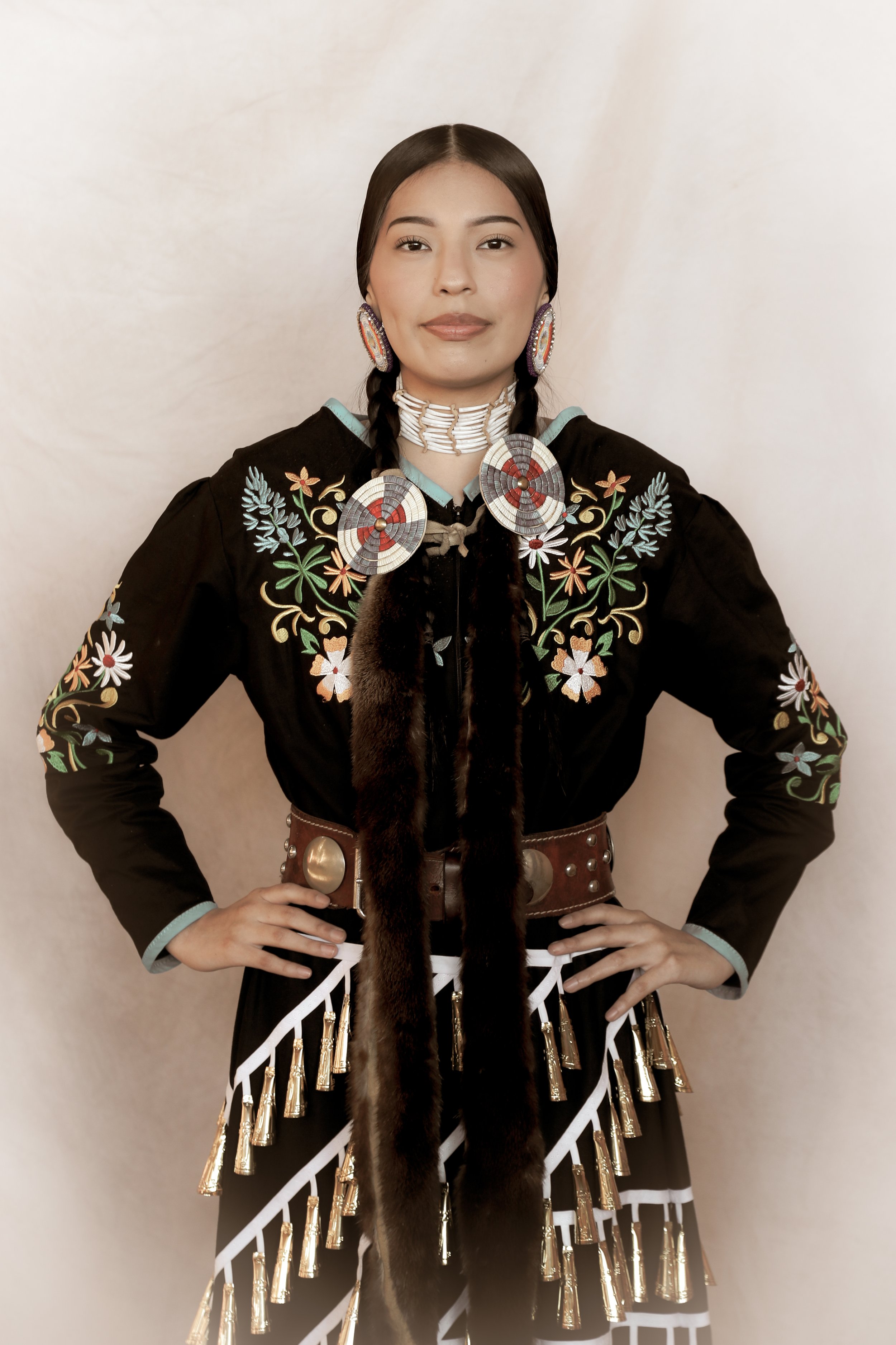 Person wearing traditional Native American attire with intricate embroidery and beadwork, including a decorated belt and accessories.