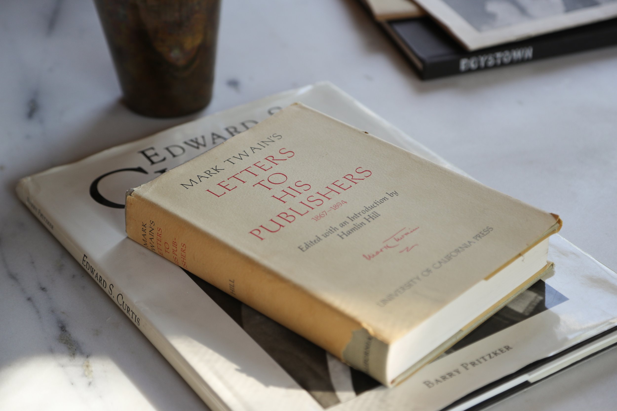 Books on a table including 'Mark Twain's Letters to His Publishers' and titles by Edward S. Curtis and Barry Pritzker.