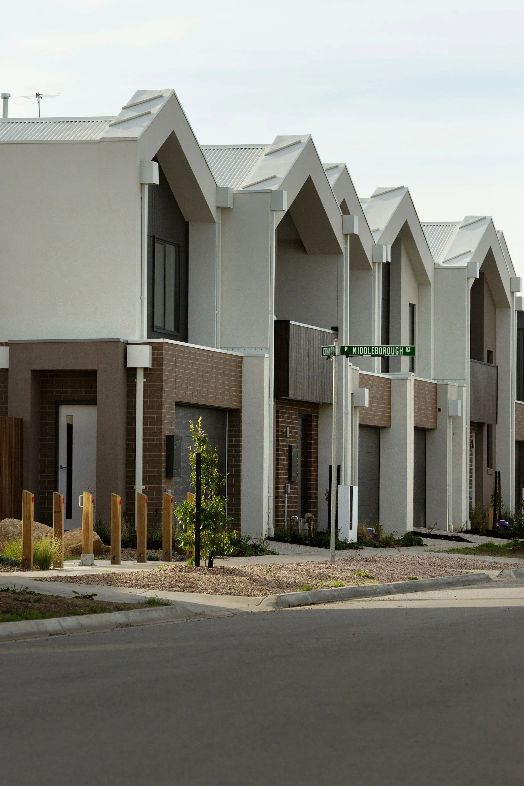Modern residential row houses with a minimalist design, white and brown exterior, small front yard, and a street sign that reads Middleborough.