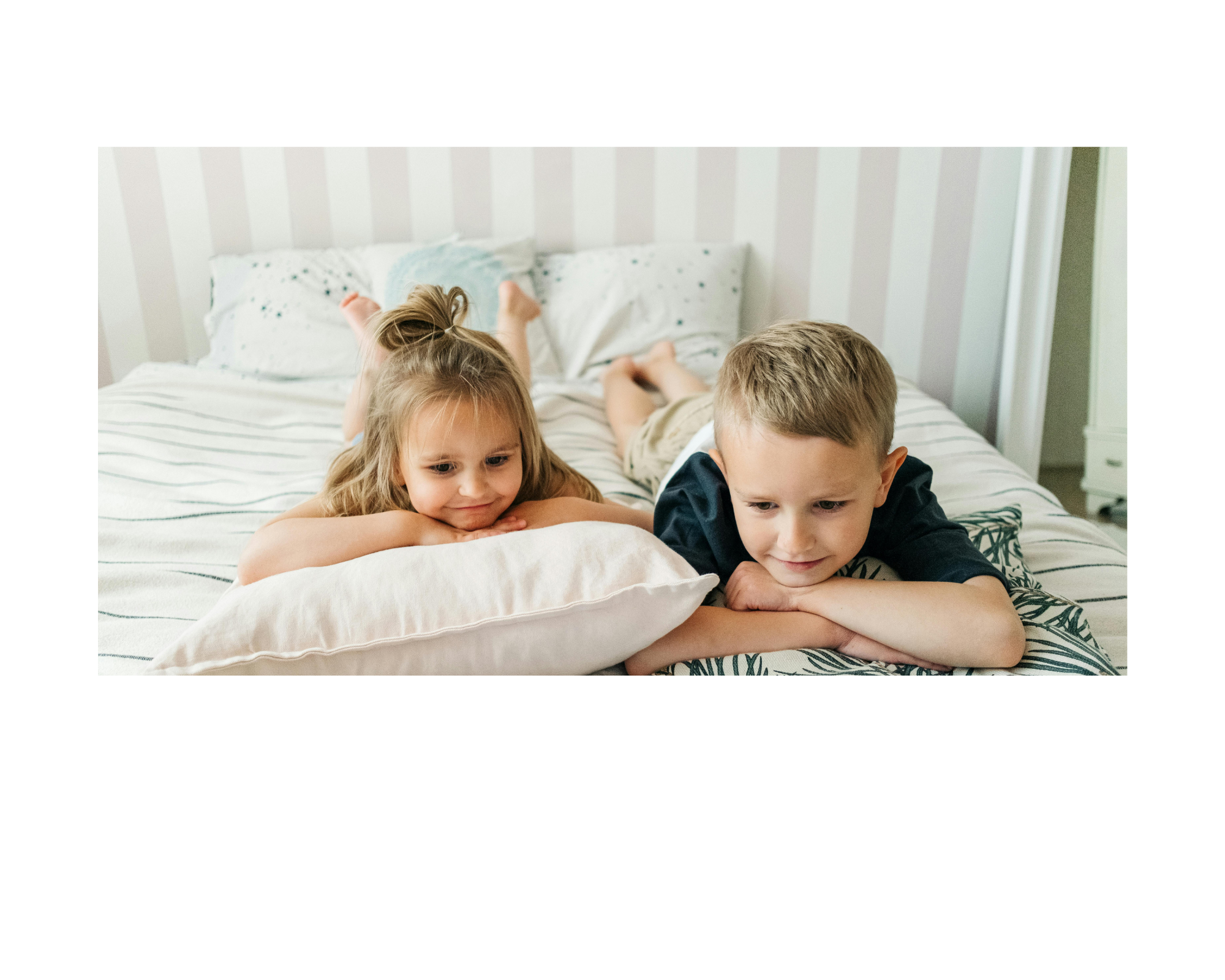 A young boy and girl laying in bed with smile on face.