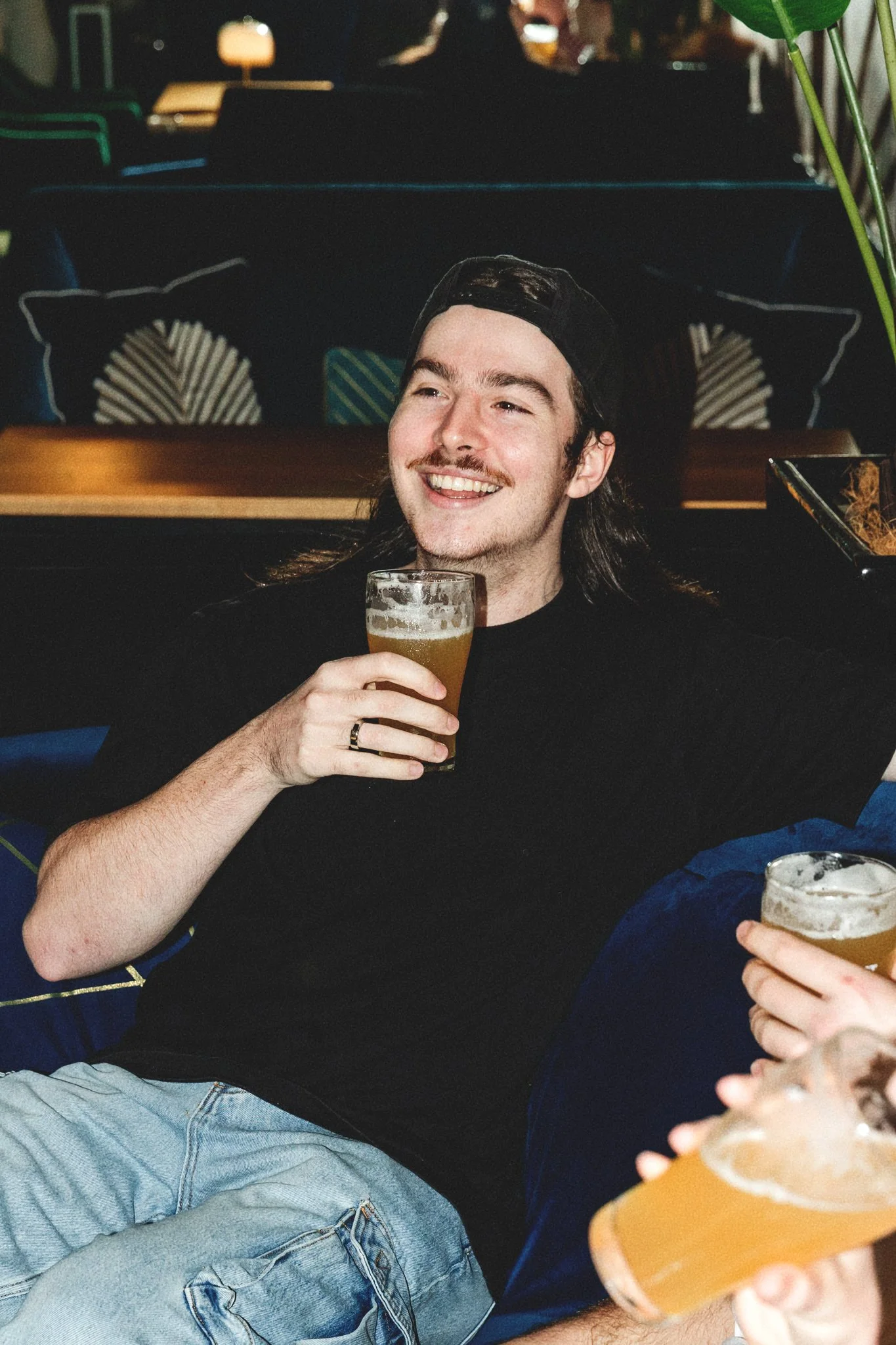 Two glasses of beer with foam on top, placed on a bar mat with the word 'HEADSTART' printed on the glass in the foreground. The background is blurred.