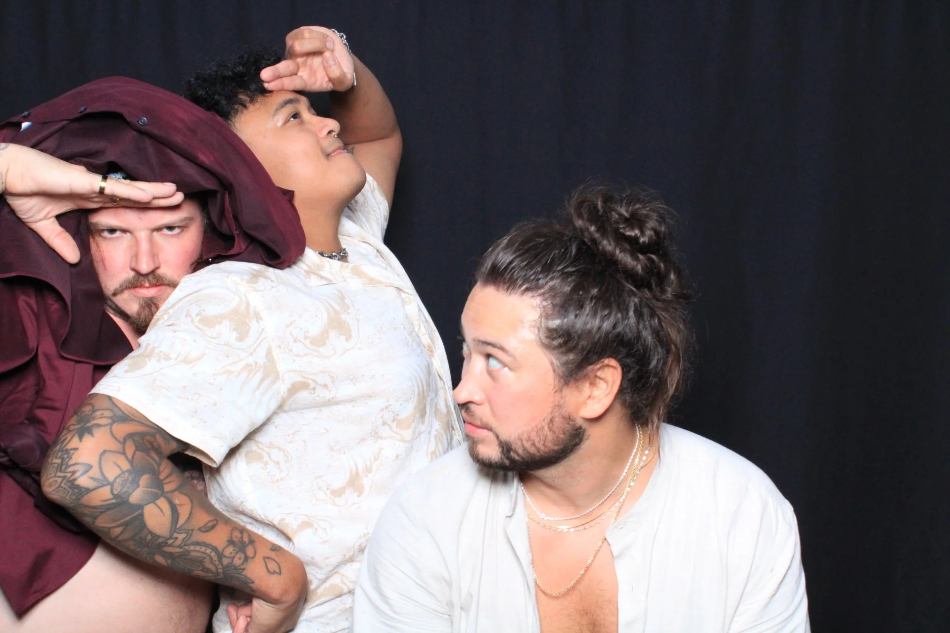 Three people posing against a black background, with the person in the middle looking upwards and the other two looking at her, creating a playful and adventurous mood.