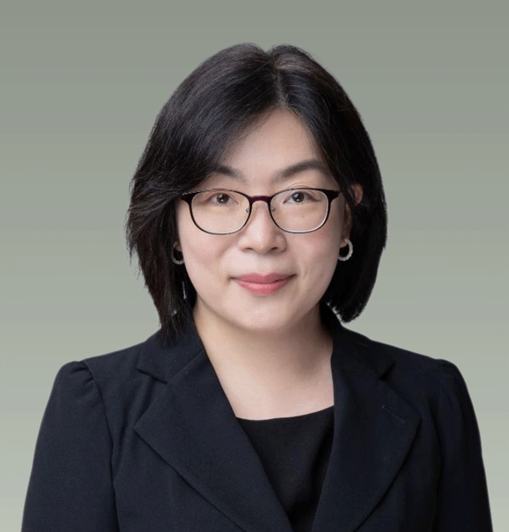 A professional woman with shoulder-length dark hair, glasses, earrings, and a black blazer smiling at the camera against a plain background.