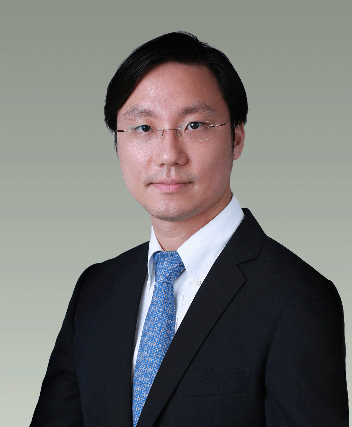 Professional headshot of a man in a suit and glasses, against a plain background.