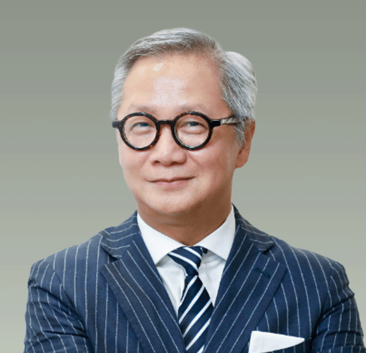 A middle-aged man with gray hair, wearing round black glasses, a dark pinstripe suit, a white dress shirt, and a striped tie, smiling slightly against a plain gray background.