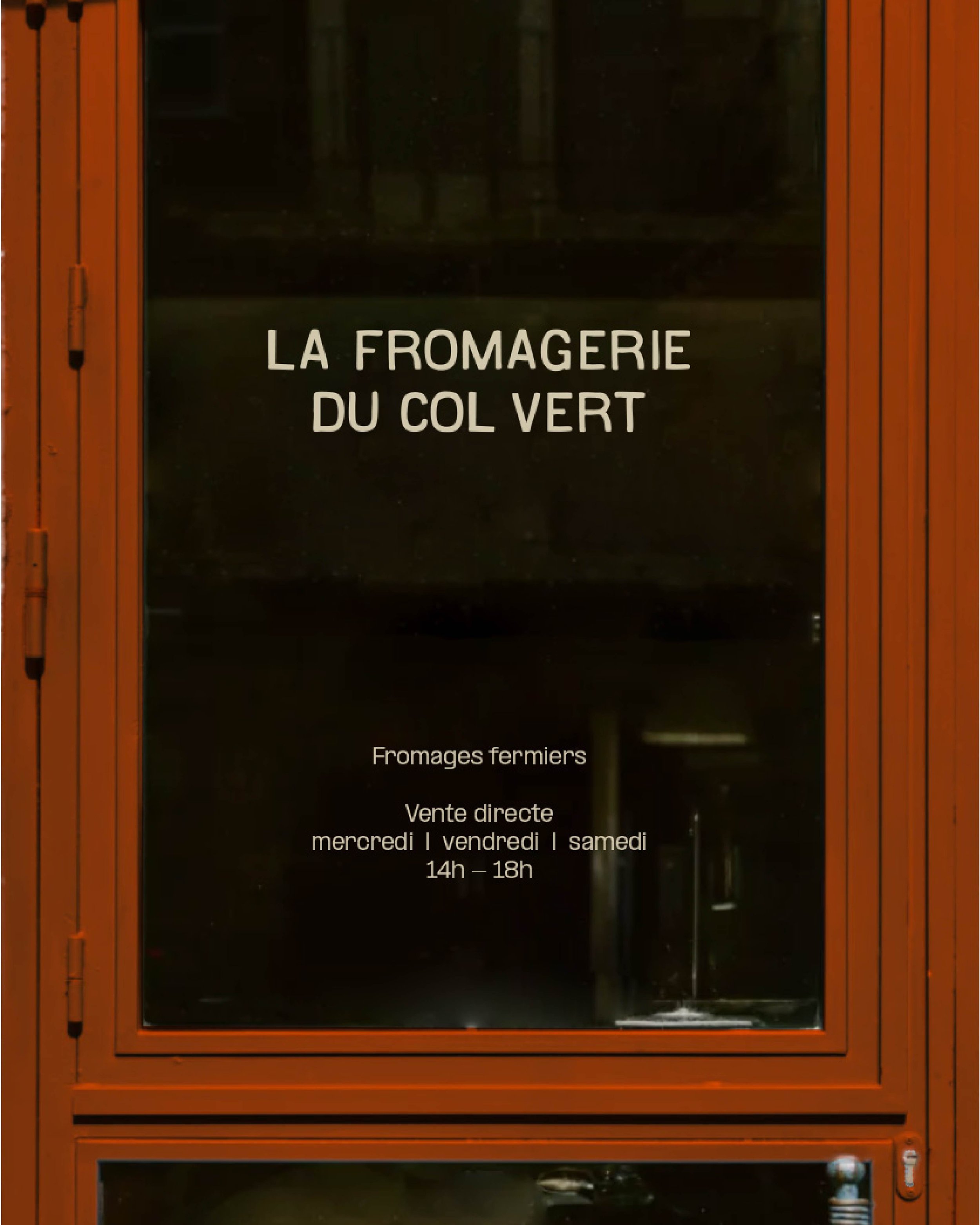 Vitrine en bois orange avec inscription blanche indiquant une fromagerie du Col Vert, vendant des fromages fermiers en vente directe du mercredi au samedi de 14h à 18h.