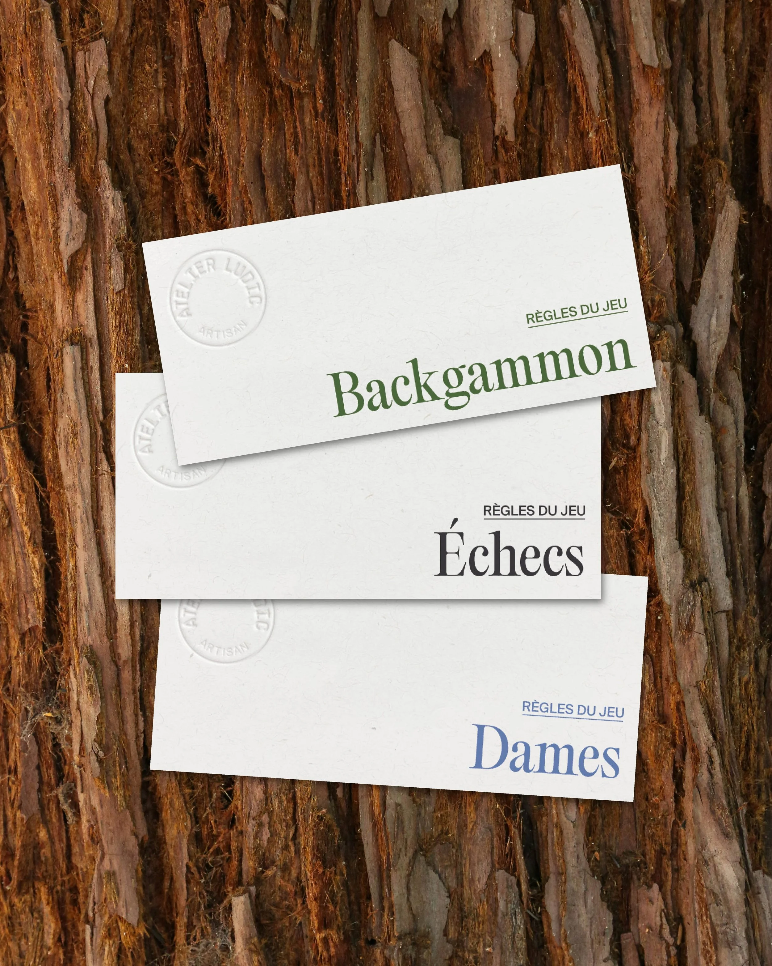Trois cartes de jeu de badminton agencées en diagonale contre un fond de tronc d'arbre.