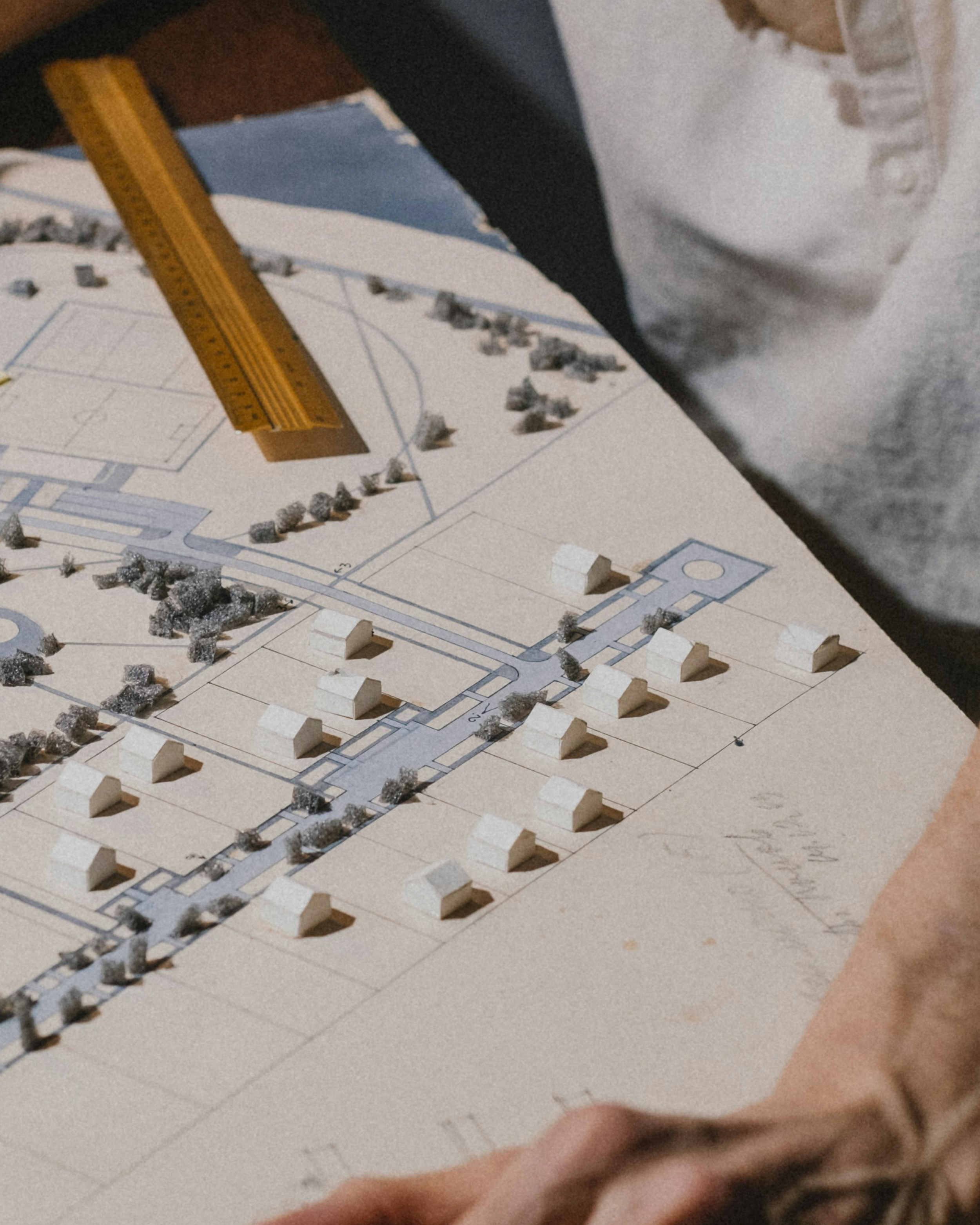 Plan d'urbanisme avec petites maquettes de bâtiments et un règle jaune.