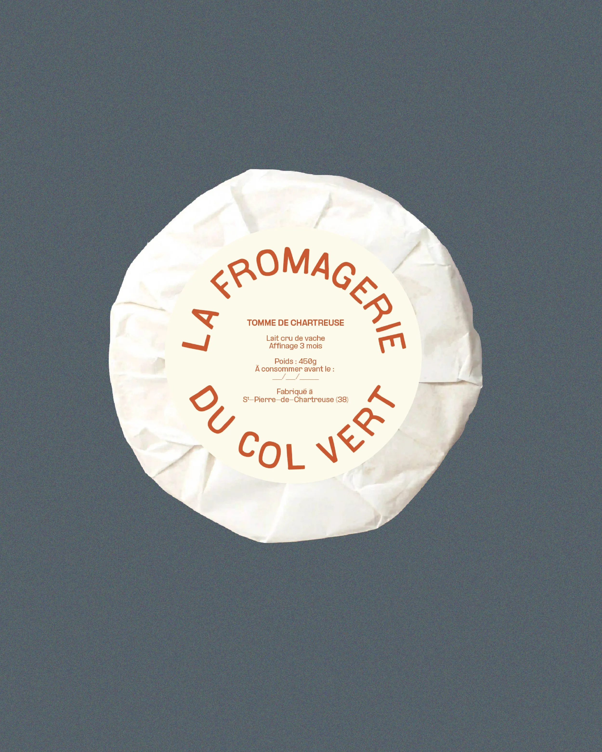 fromage de chèvre en fromage de fromage, emballé dans une couche de papier blanc, avec une étiquette ronde beige portant la description en français.
