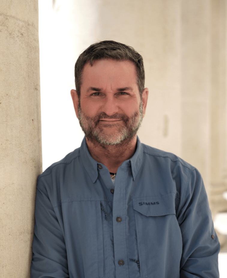 Mann mit Bart und einem blauen Hemd lehnt an einer grauen Säule, Sinnbild für mentale Gesundheit in München