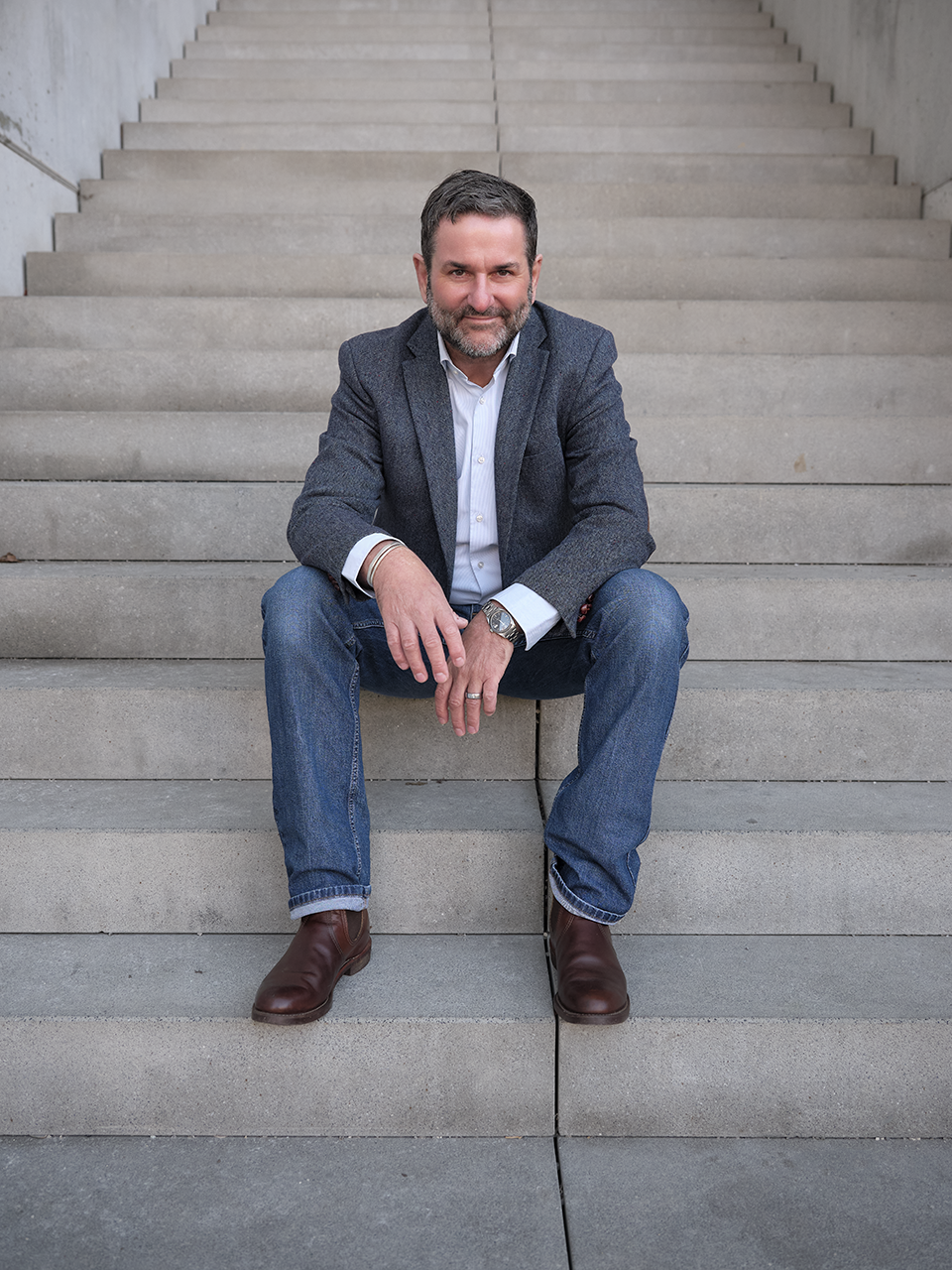 Ralf Kratzert, Coach für mentale Gesundheit und Resilienz in München, sitzt auf einer Treppe