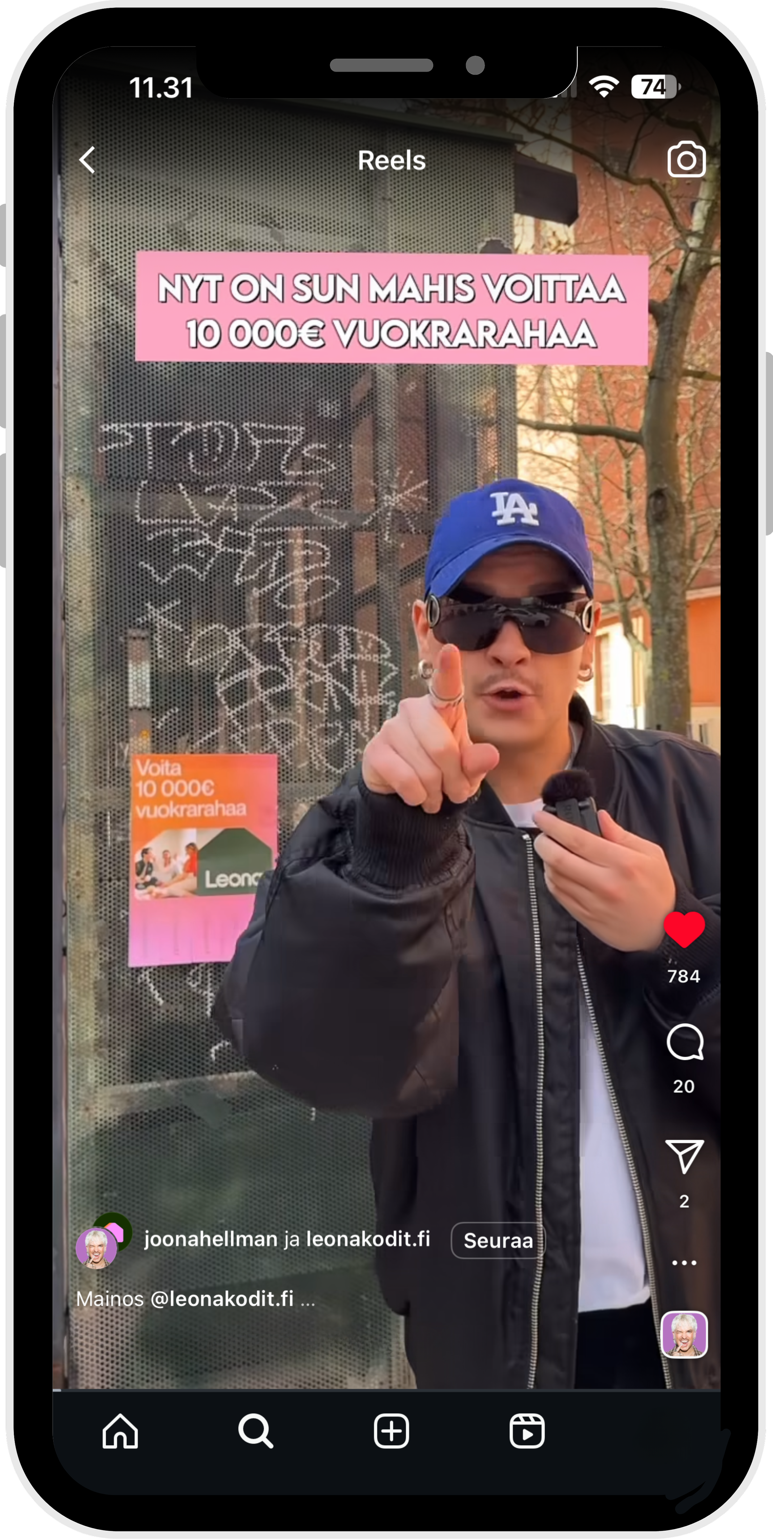 Nuori mies puhuu kameralle, taustalla bussipysäkki ja mainos, jossa lukee 'Voita 10 000e vuokrarahaa'.