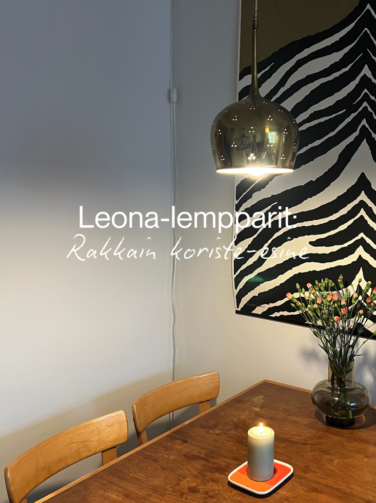 Ruokapöytä, jonka päällä on kynttilä ja maljakko kukkia. Pöydän ympärillä on kolme puista tuolia. Seinällä on mustavalkoinen zebra-taulu.