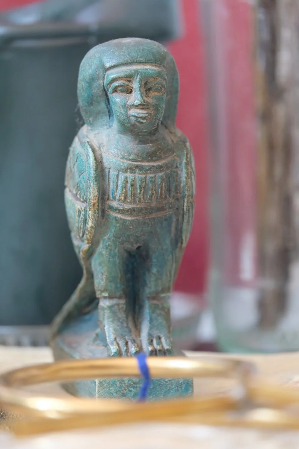 Kleurruine oude Egyptische beeldhouwwerk van een menselijke figuur met een dierlijk hoofd, waarschijnlijk een krokodil of andere waterbewonende dier, op een houten ondergrond.