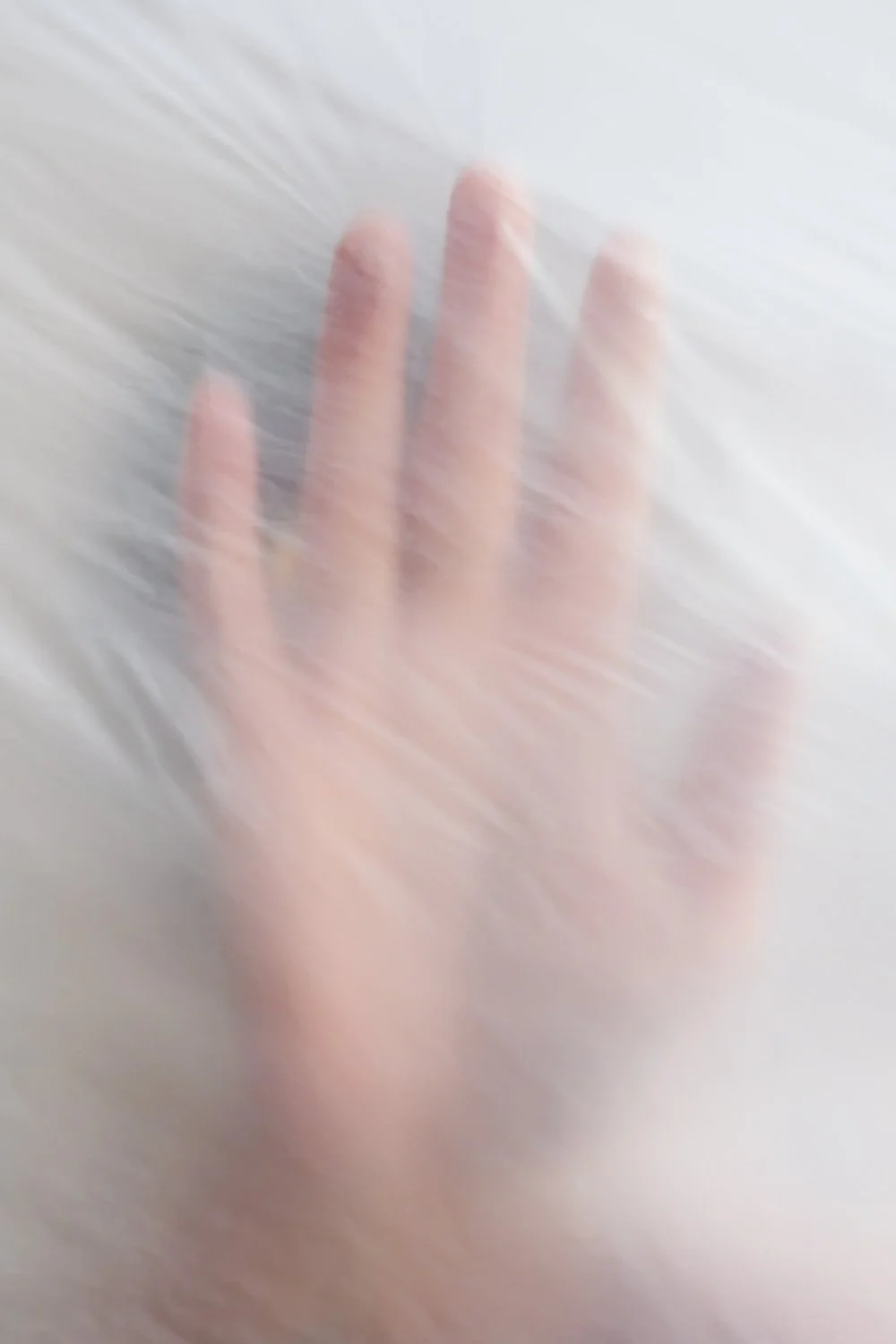 Een hand die tegen een doorzichtige plastic folie drukt, waardoor de vinger niet duidelijk zichtbaar is en de foto wazig is.