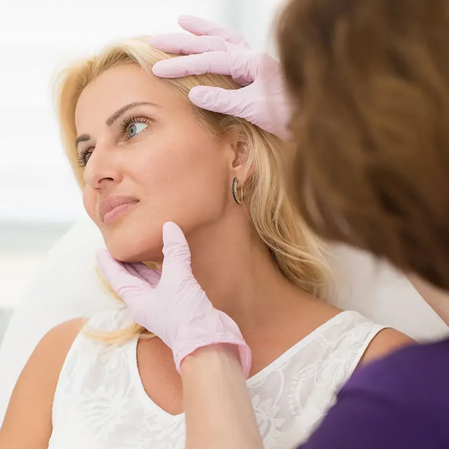 Woman undergoing a facial assessment with a practitioner examining her skin and facial contours