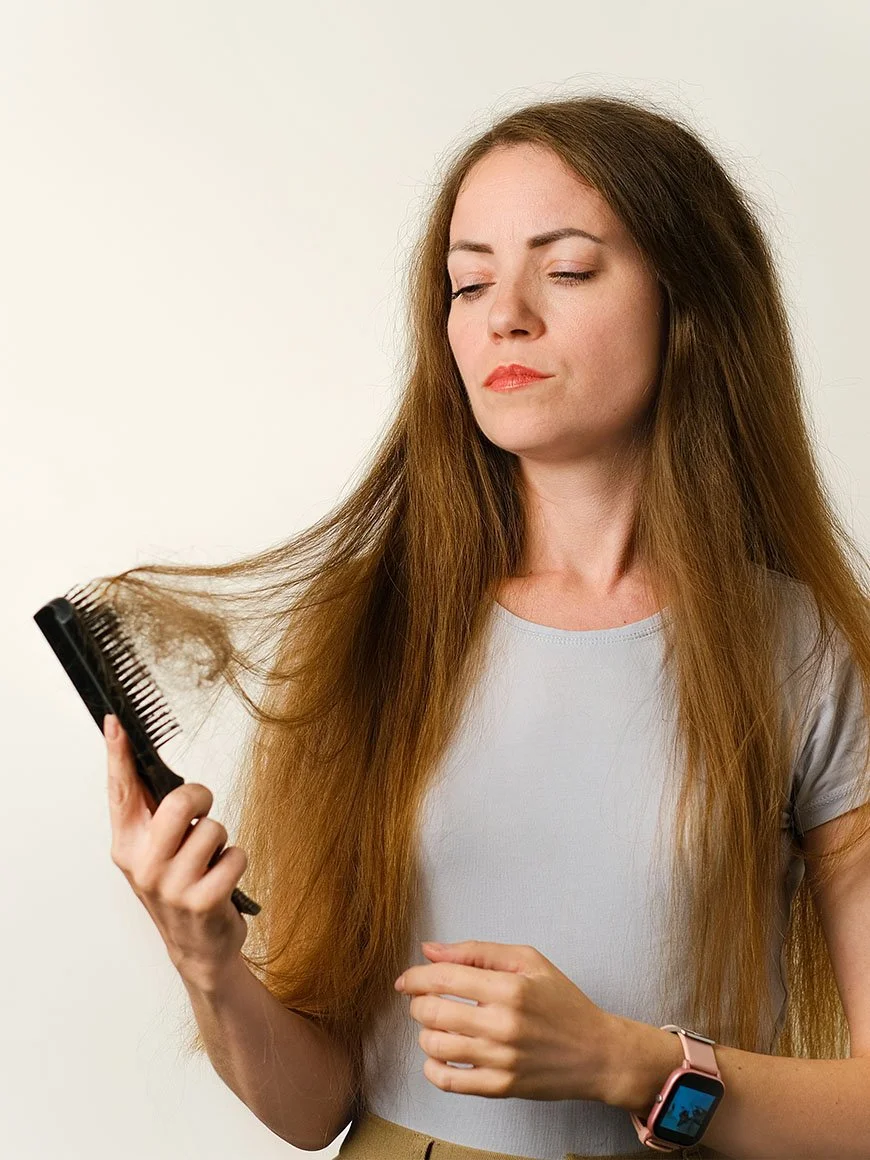 A woman holding fallen hair, illustrating hair loss concerns.