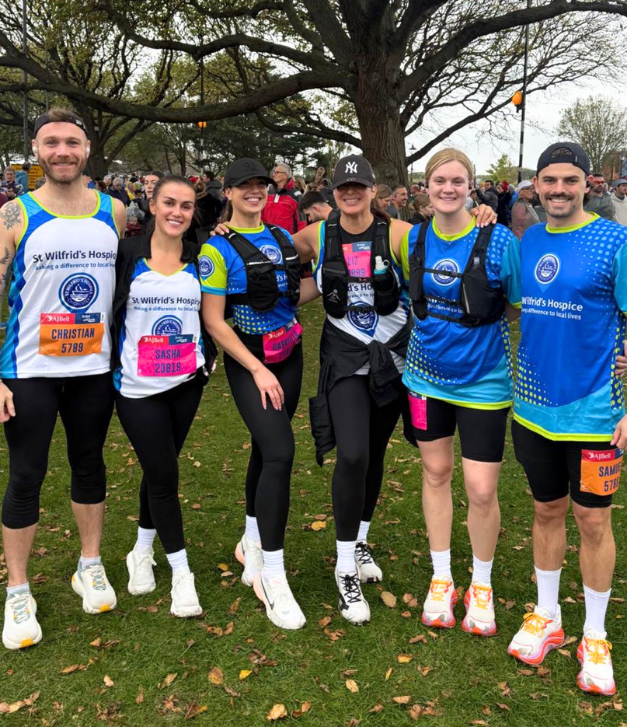 Group of six runners in colorful athletic gear posing outdoors at a race event.