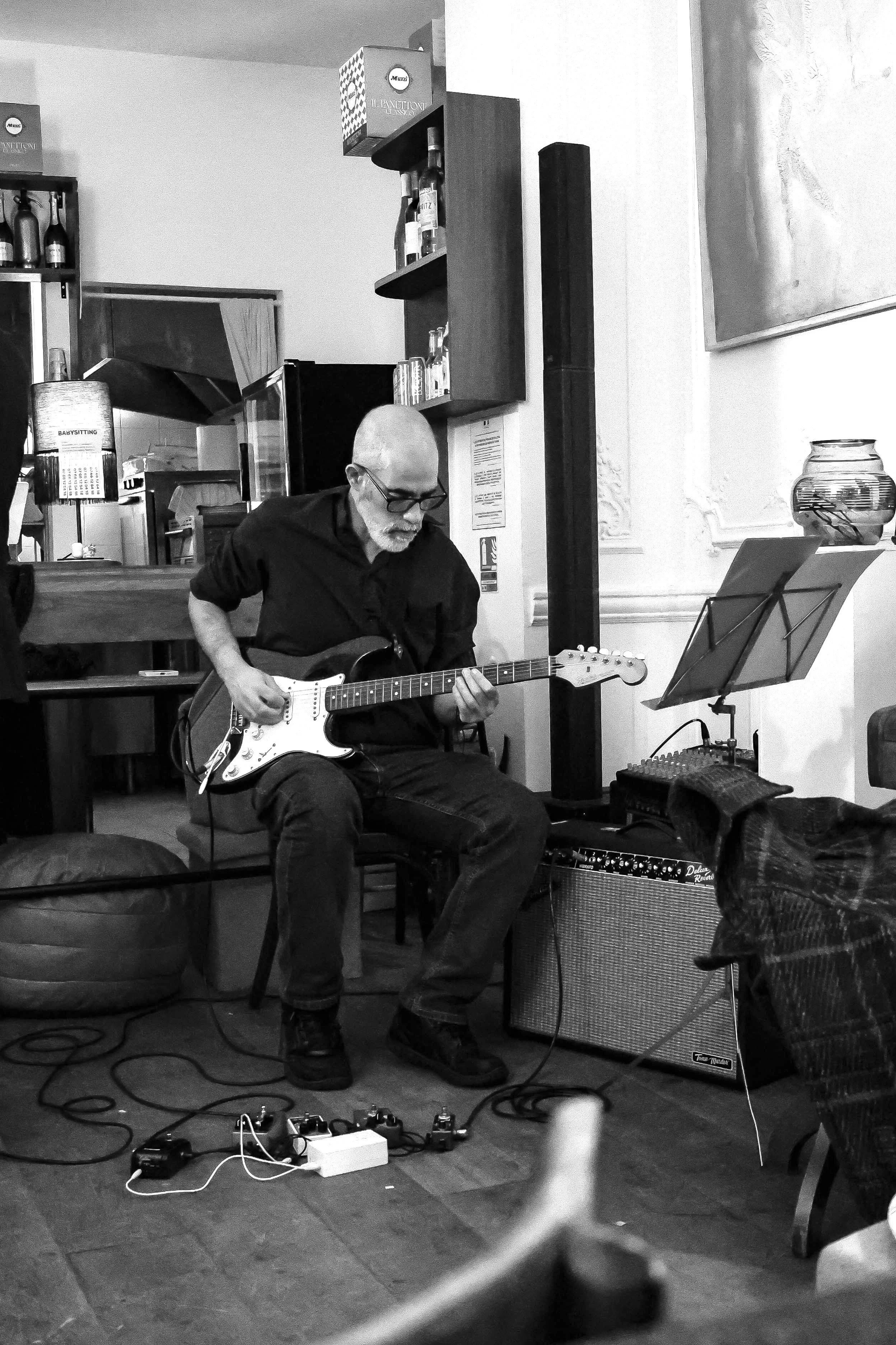 Un homme jouant de la guitare électrique lors d'une performance musicale dans un cadre intérieur.